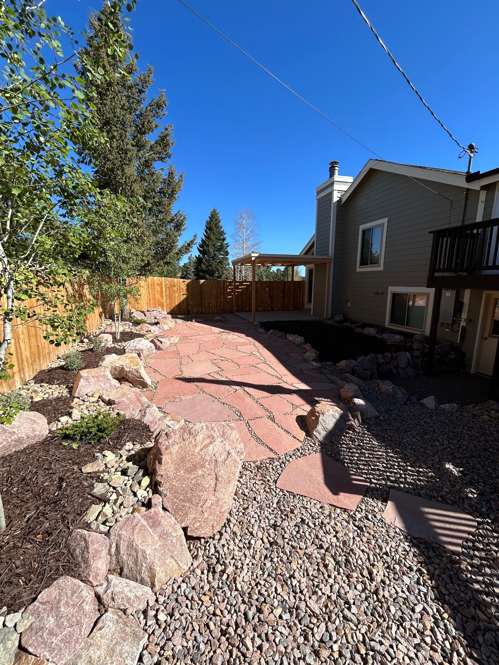 A backyard with a stone walkway leading to a house.