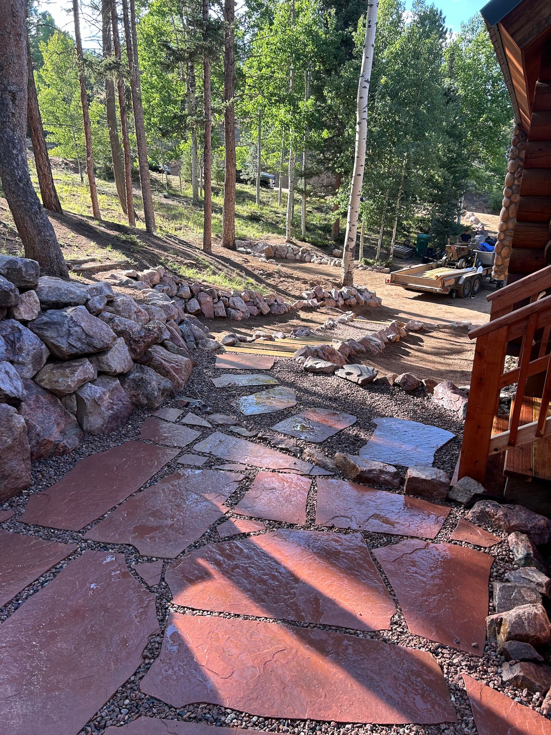 A stone walkway leading to a log cabin in the woods.