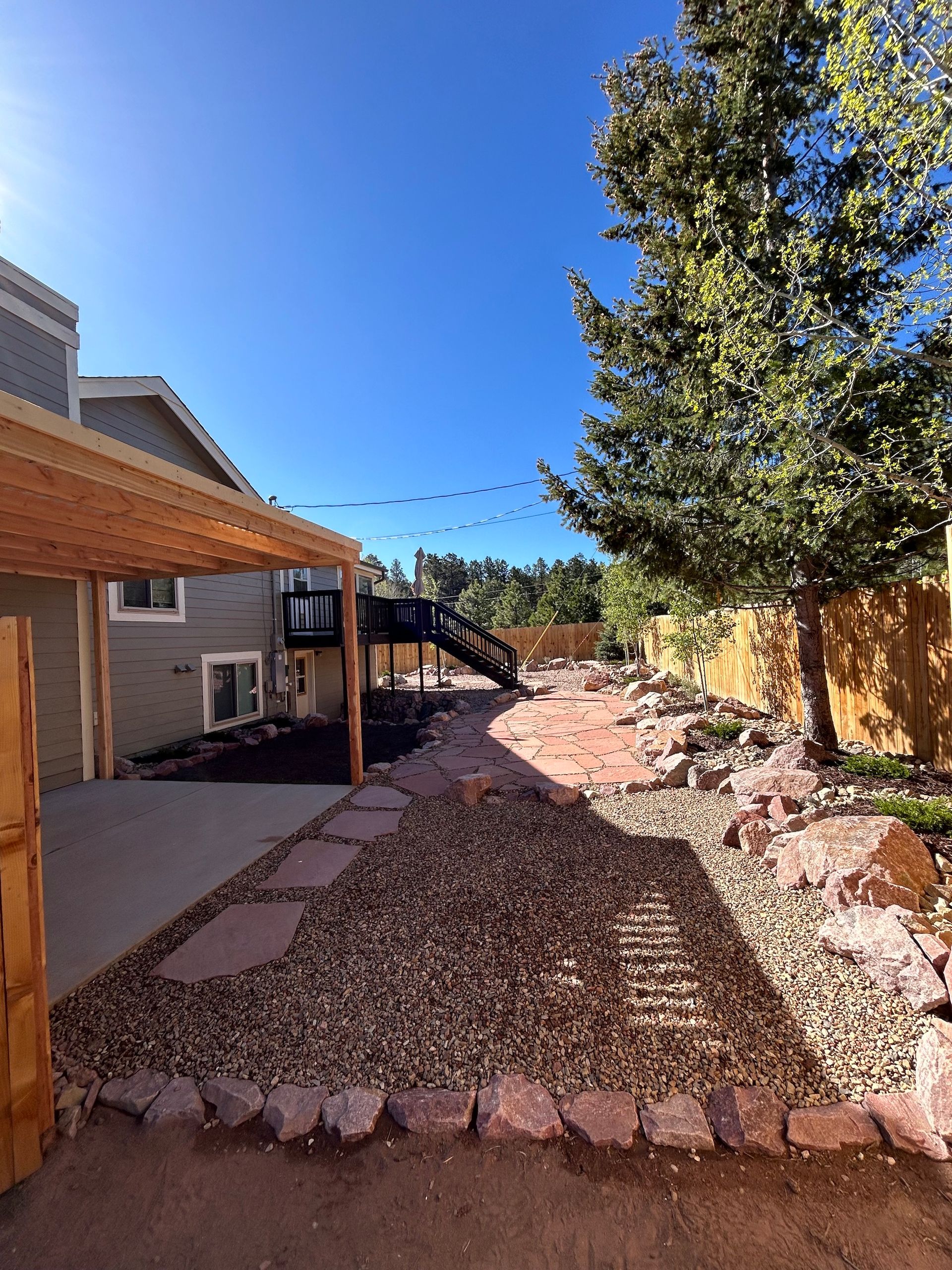 A backyard with a covered walkway and a house in the background
