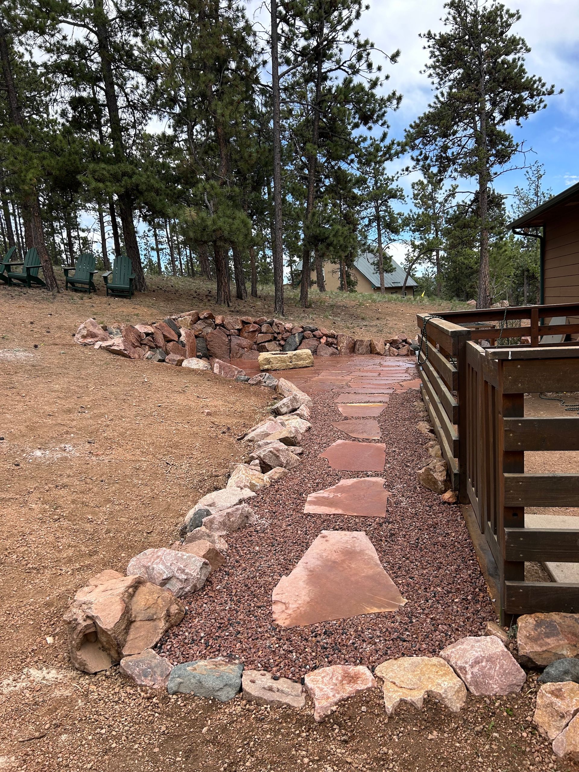 A stone walkway leading to a house in the woods.