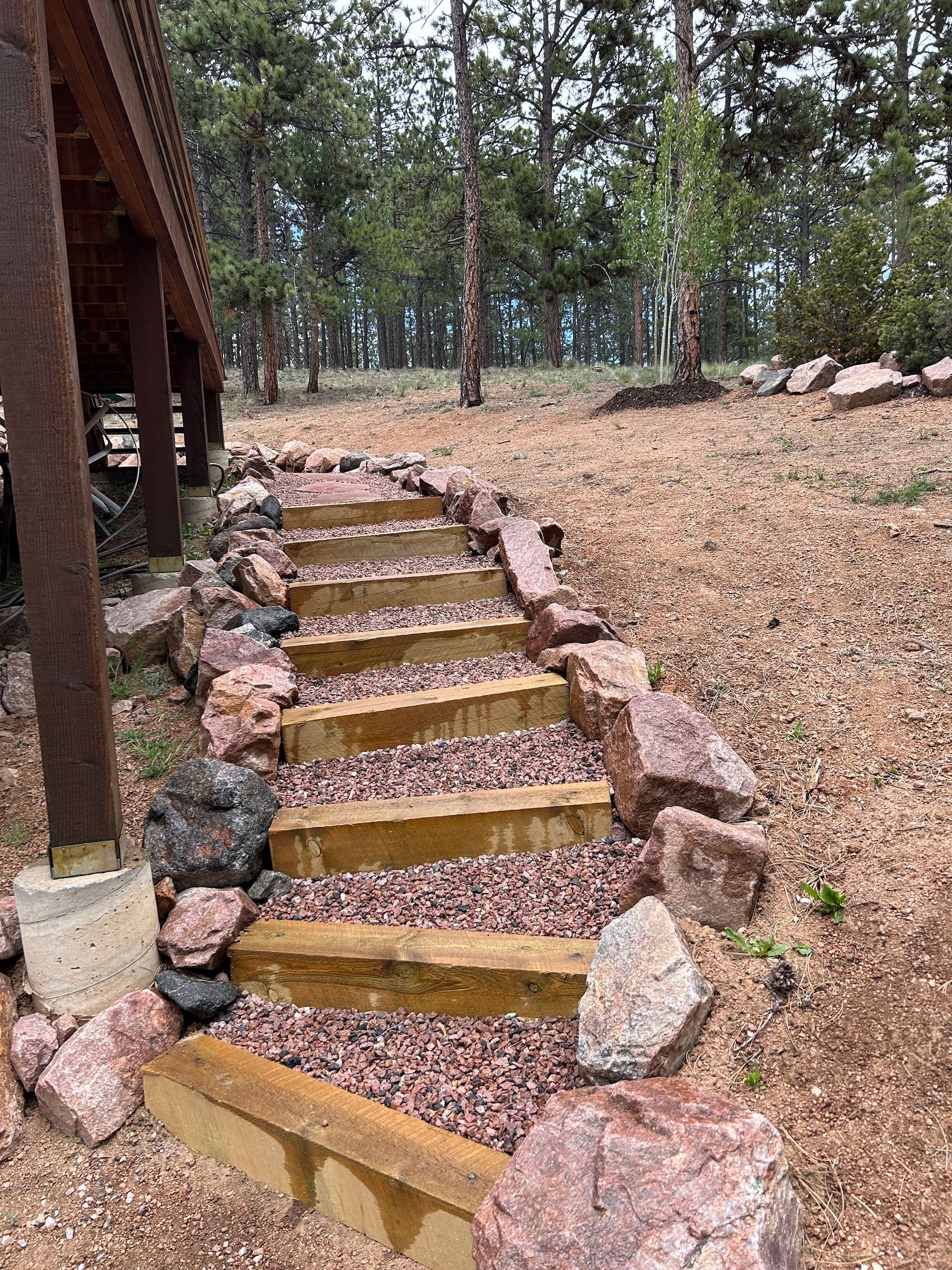A set of wooden stairs surrounded by rocks in a field.