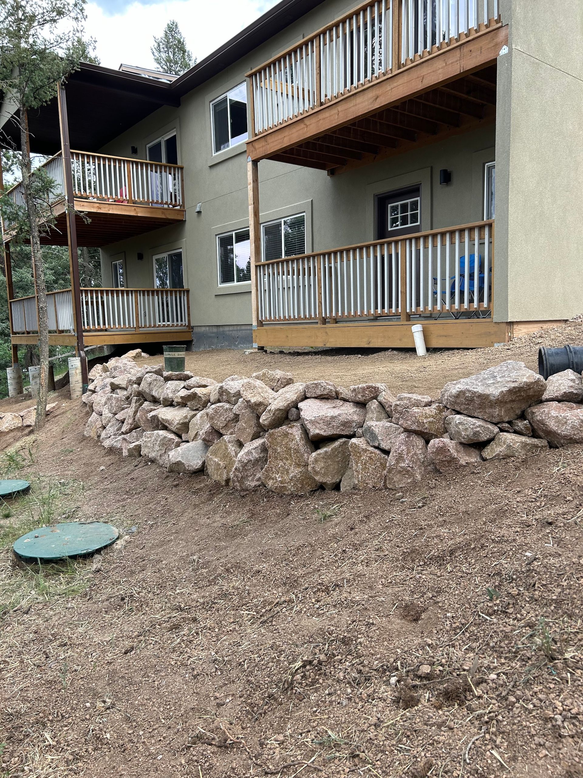 A house with a deck and a stone wall in front of it.
