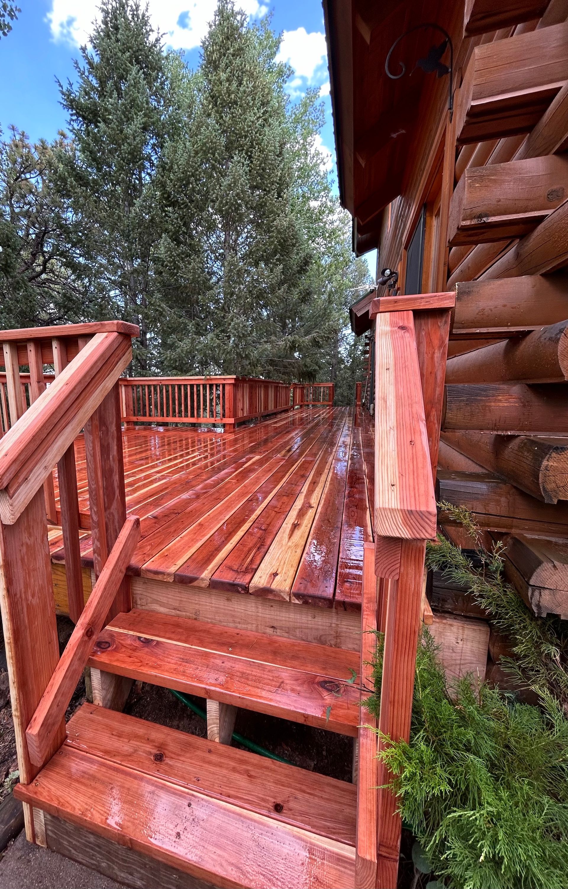 A wooden deck with stairs leading up to it next to a log cabin.