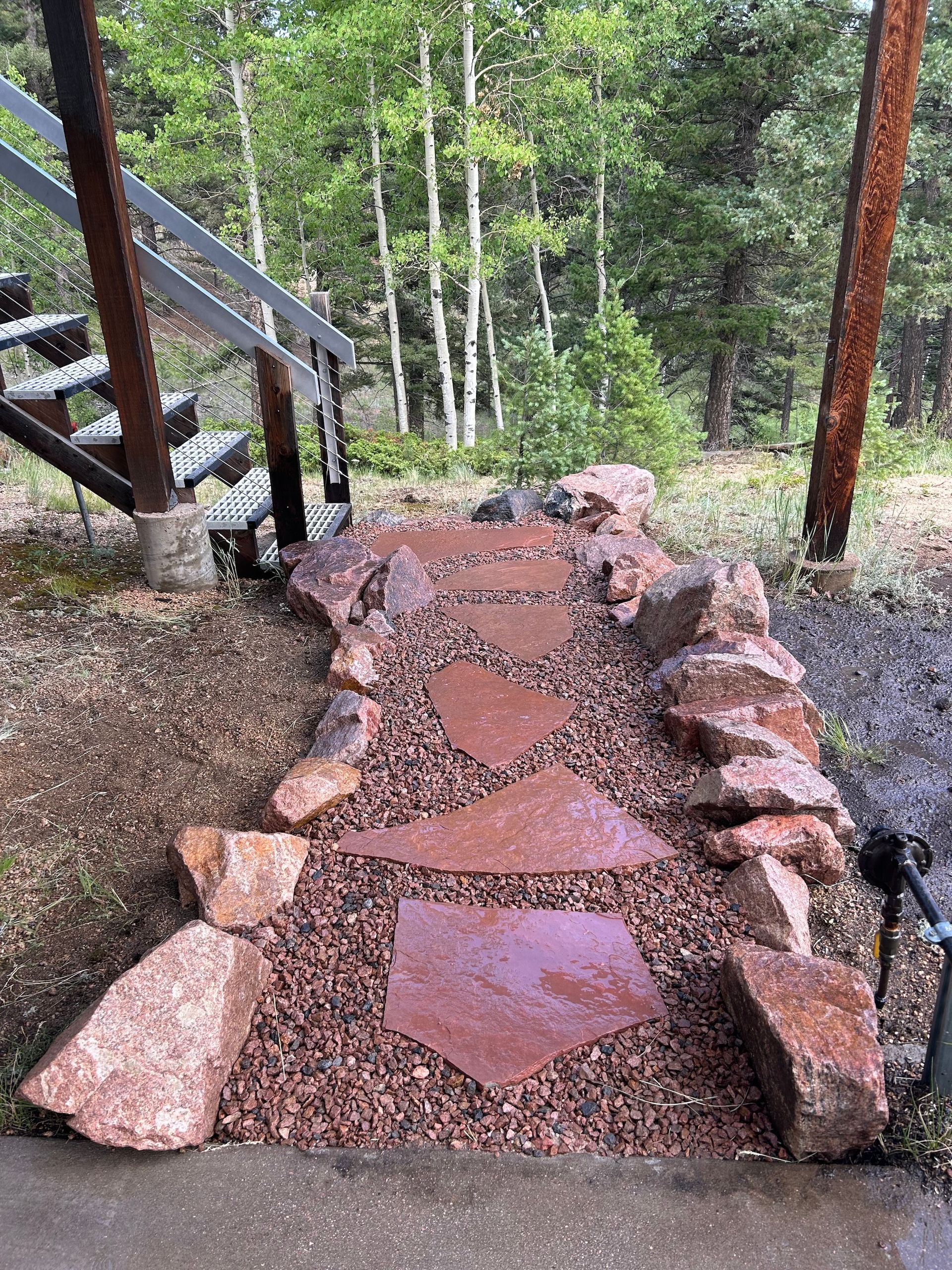 A stone walkway leading up to a set of stairs in the woods.