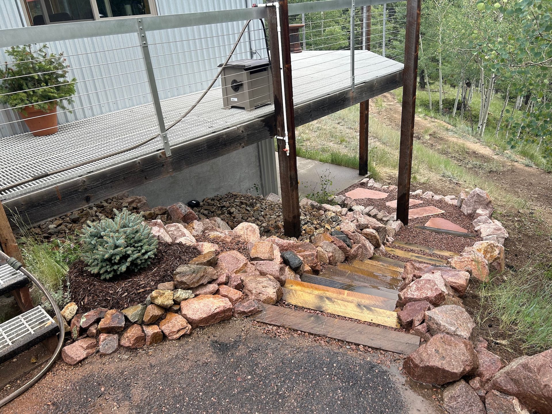 A rock garden with stairs leading up to a deck.