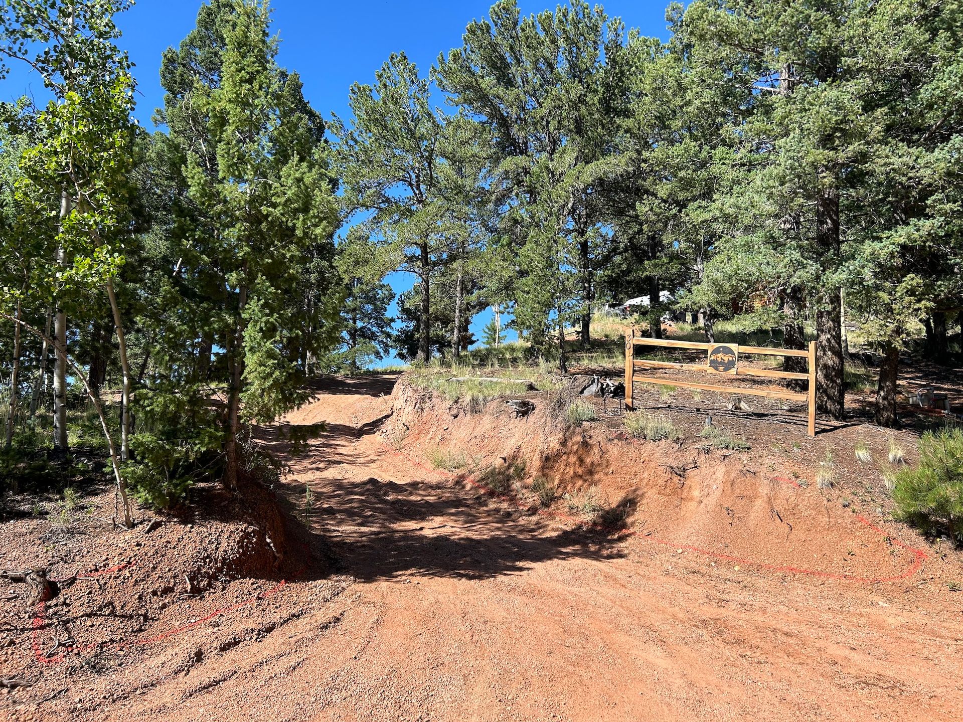 A dirt road surrounded by trees and a wooden fence.