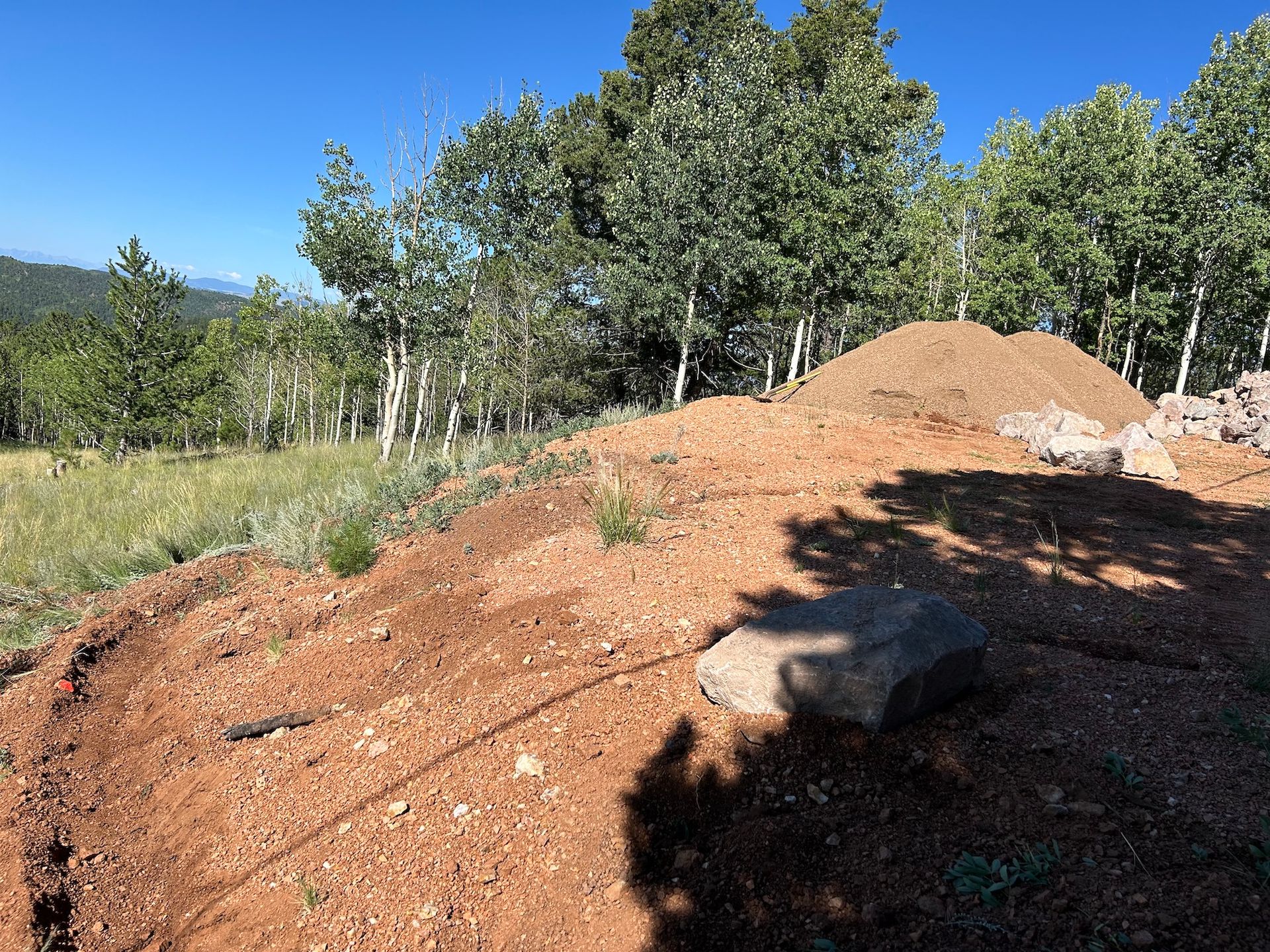 A pile of dirt is sitting on top of a hill in the middle of a field.