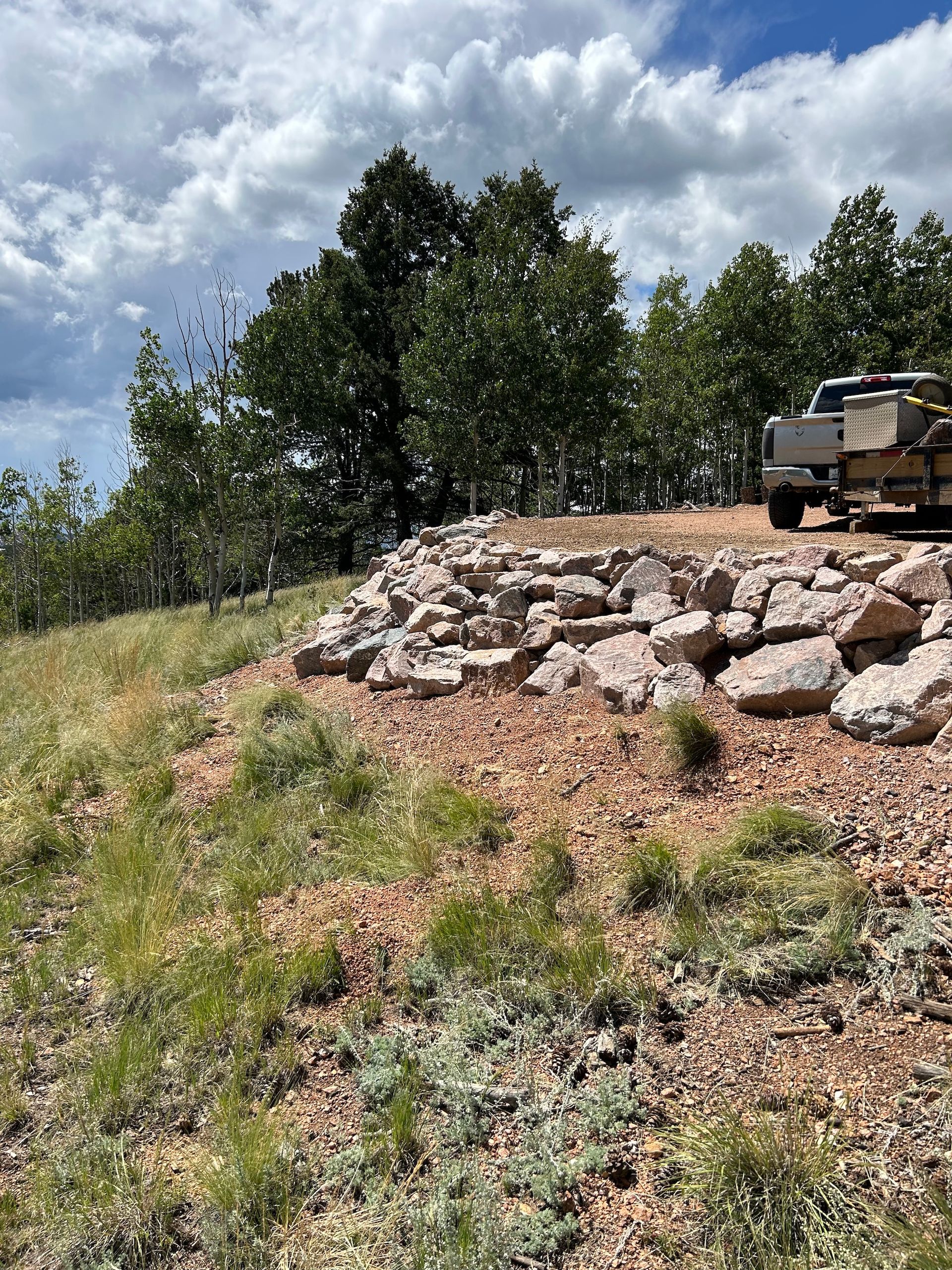 A truck is parked on top of a hill next to a pile of rocks.