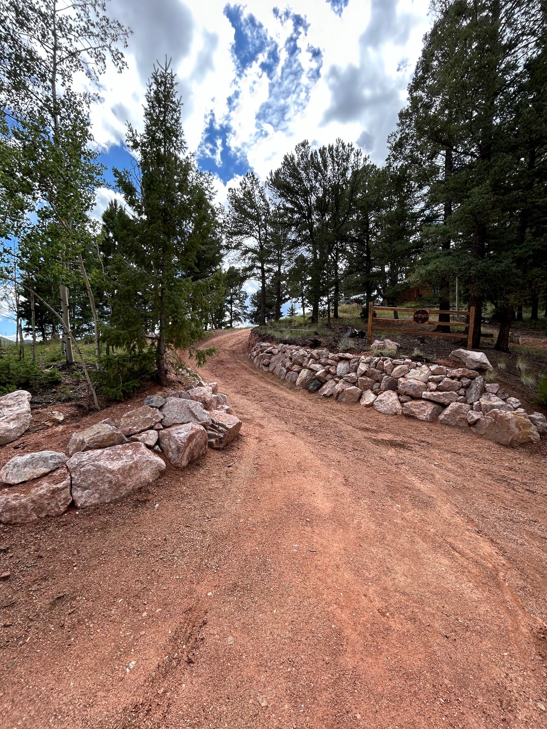 A dirt road surrounded by rocks and trees on a sunny day.