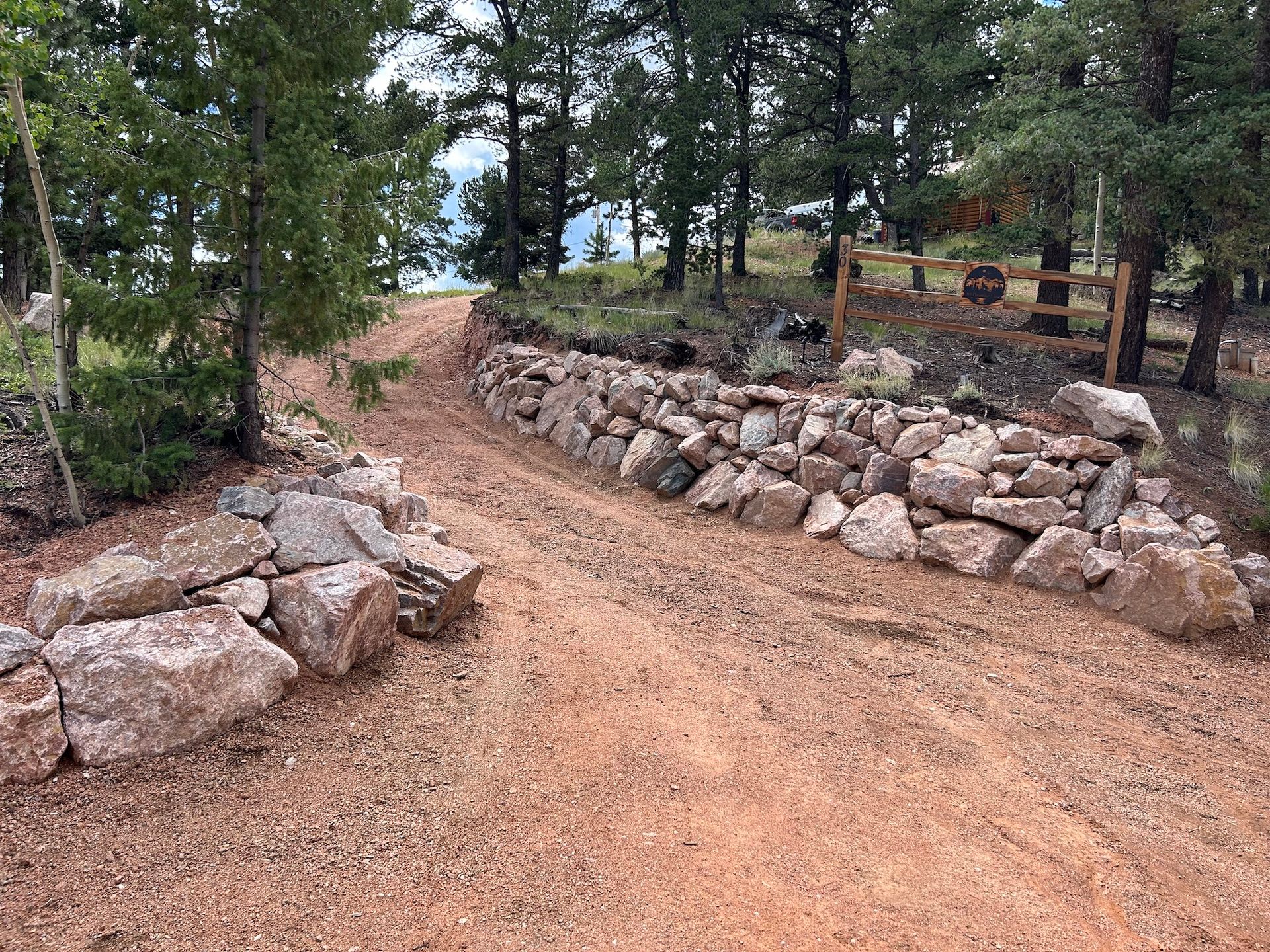 A dirt road with a stone wall on the side of it.