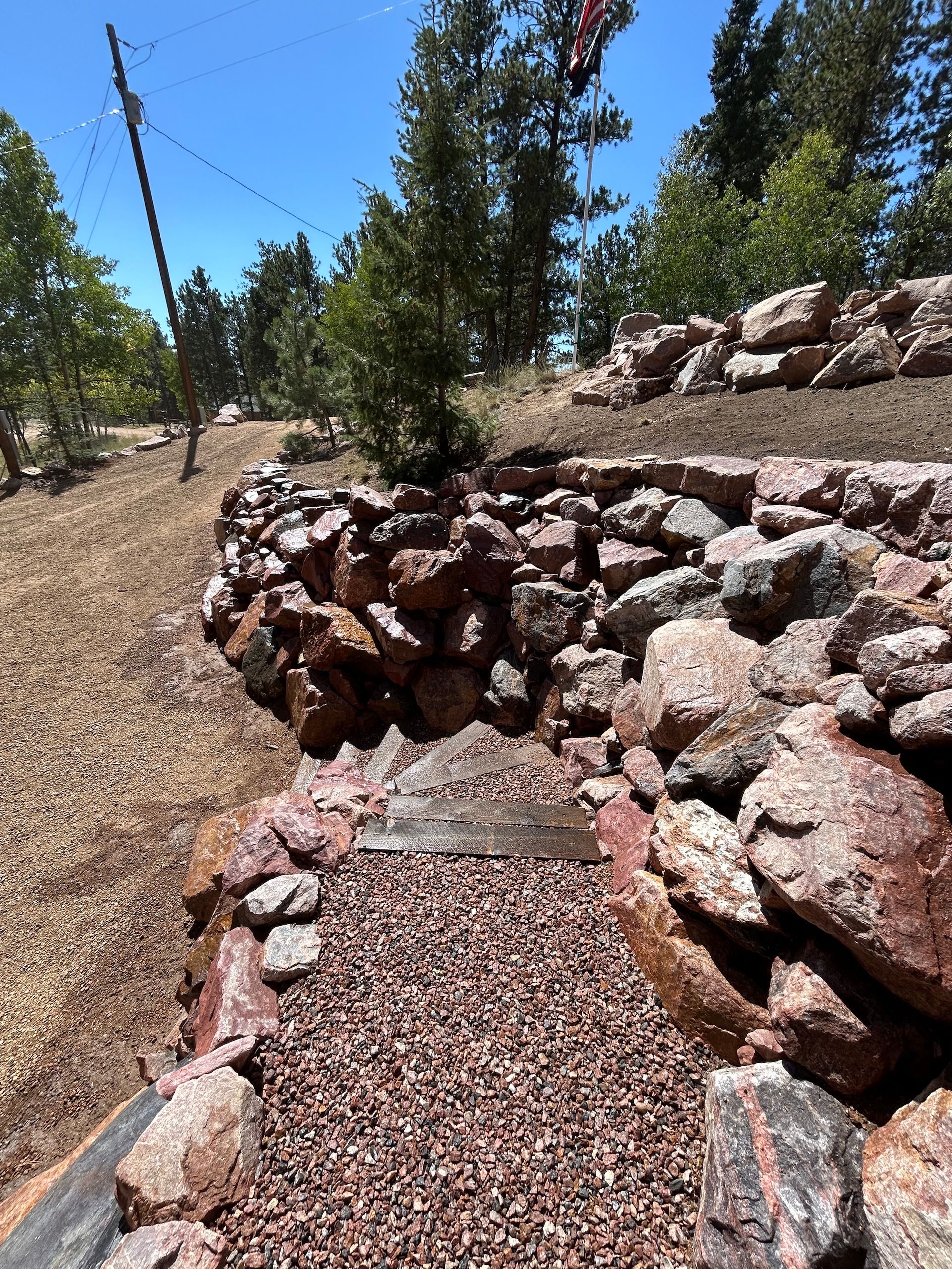 A pile of rocks and gravel in a field with trees in the background.