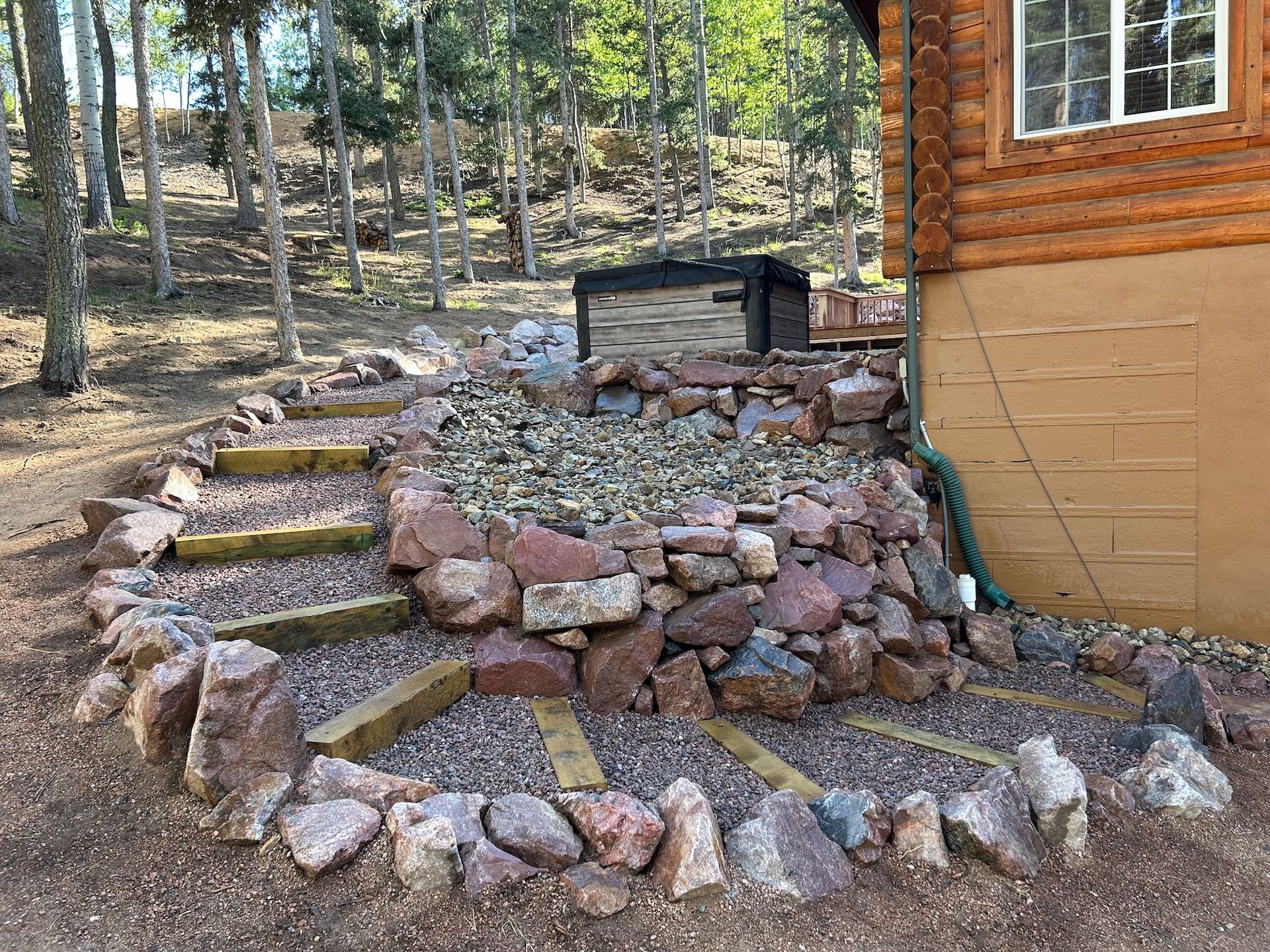 There is a rock wall in front of a log cabin.