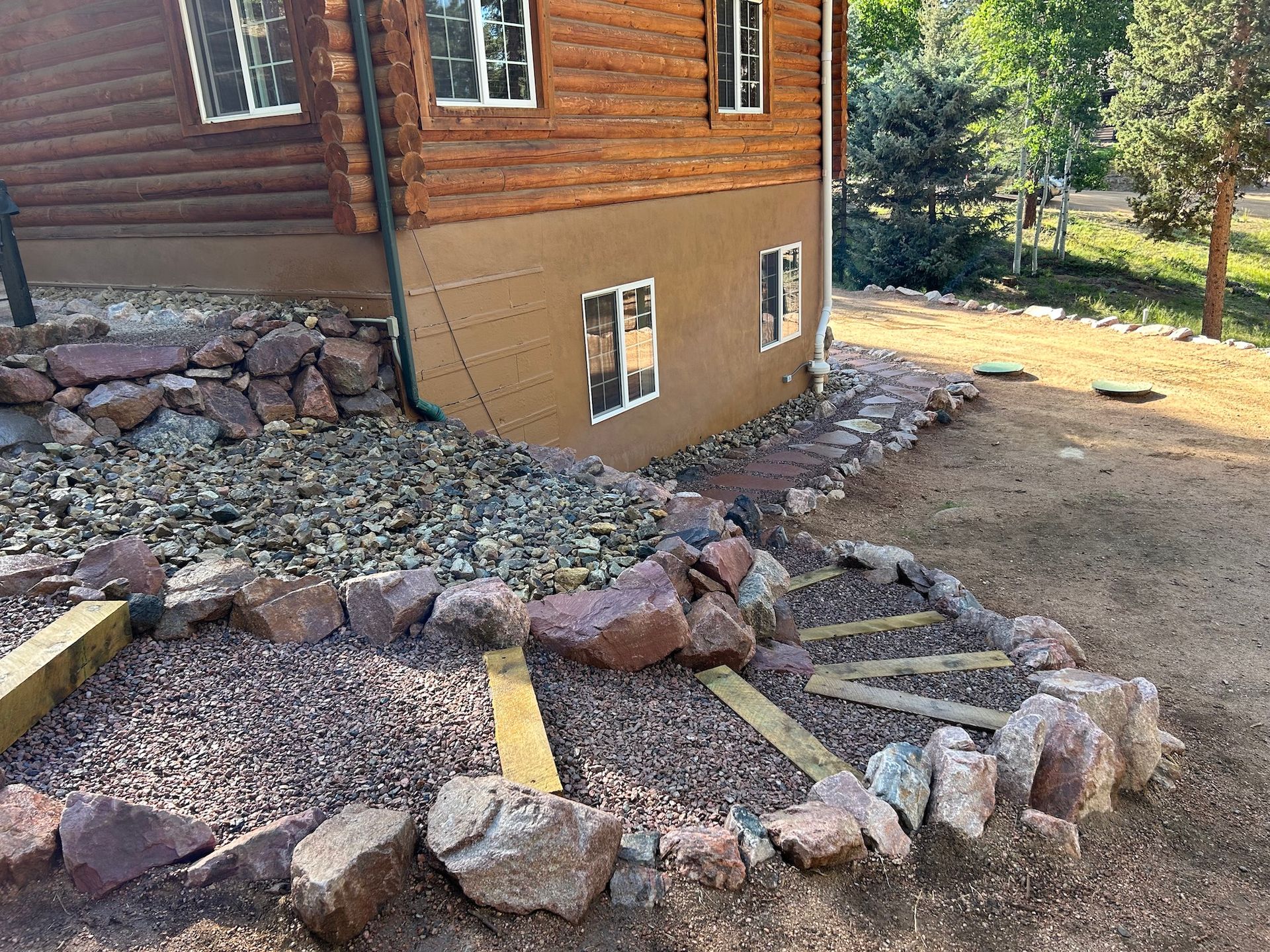 A log cabin with a rock garden in front of it.