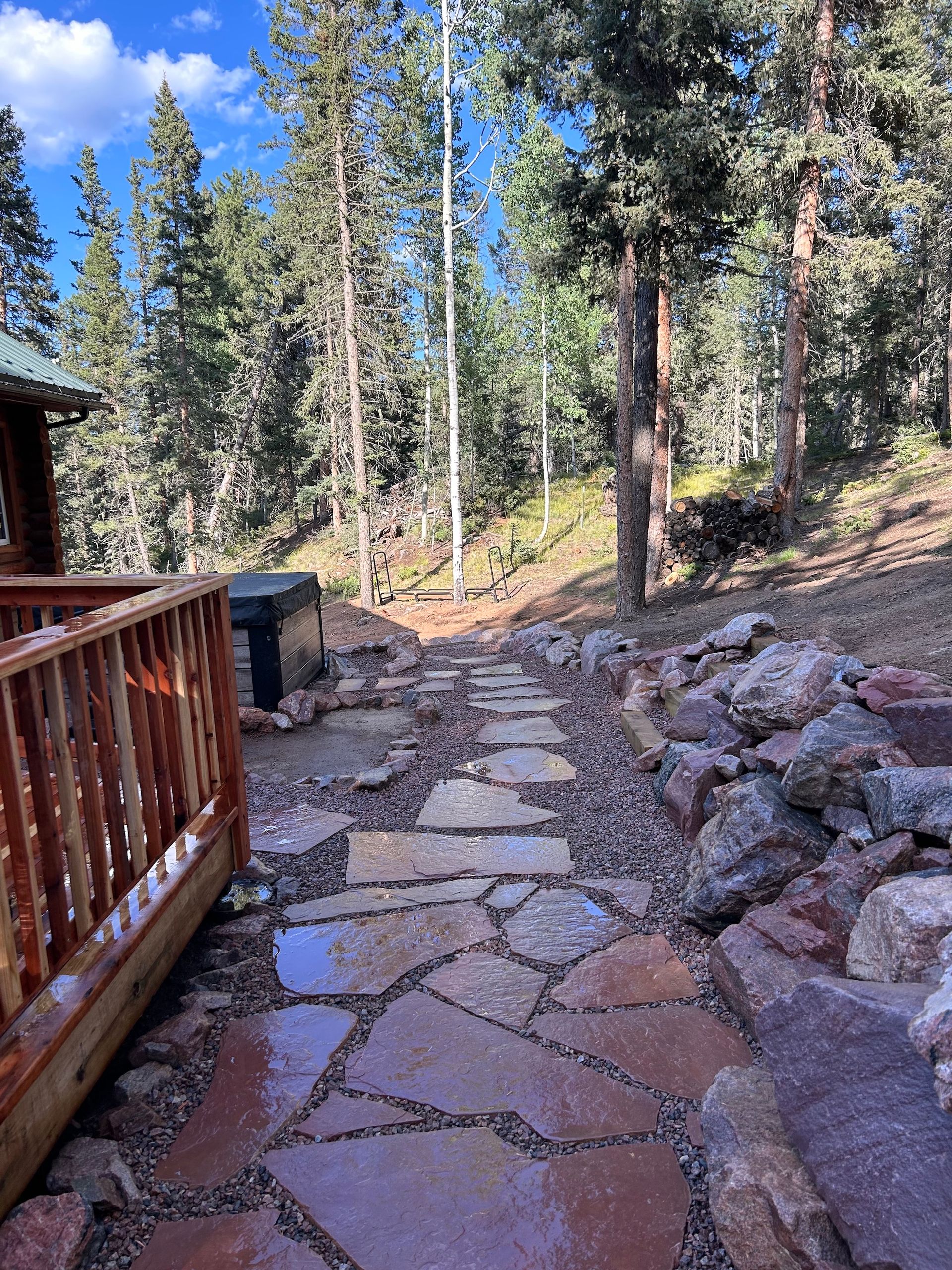 A stone walkway leading to a cabin in the woods.
