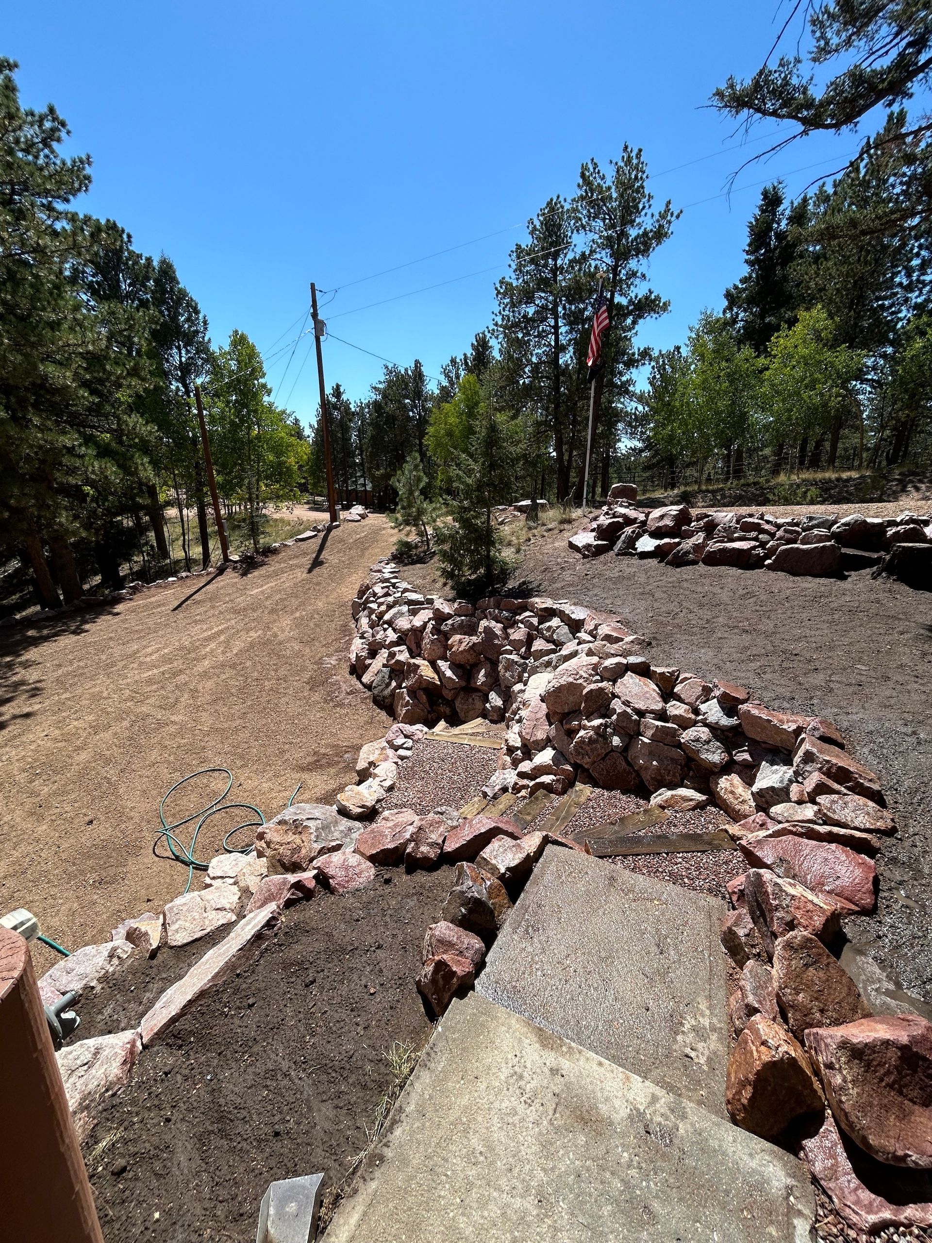A rocky area with trees in the background and a blue sky