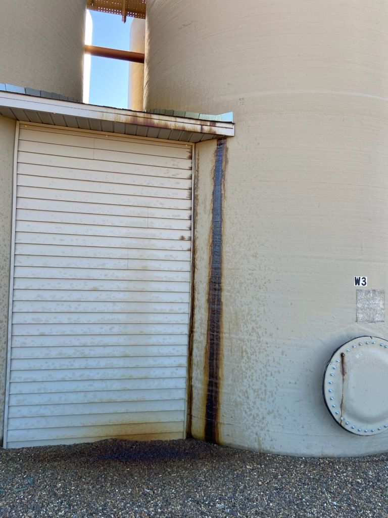 Closed white roll-up door beside a beige wall with a round utility meter and small signs.