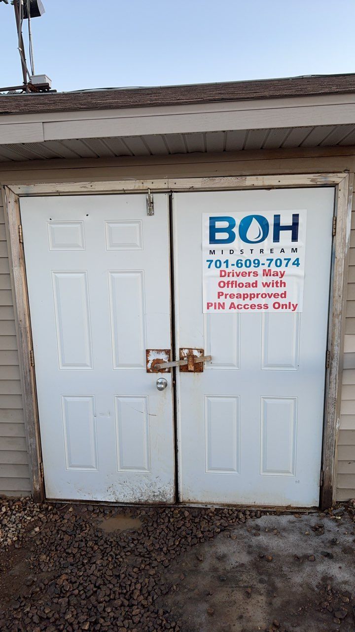 White double doors with a “BOH” sign and contact information on a small utility building.