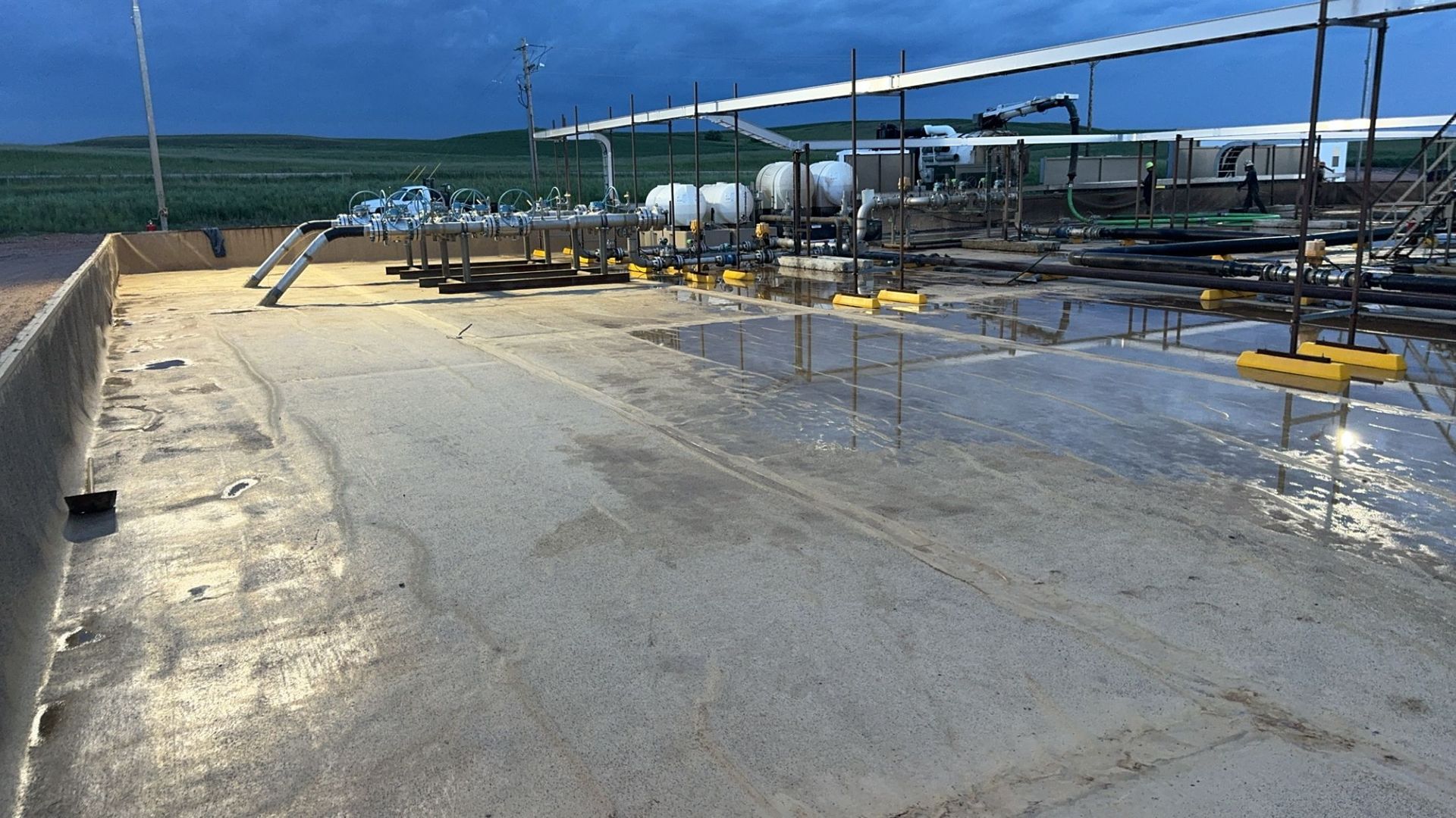 Sunlit rooftop construction area with wet concrete, rebar, and blue sky overhead