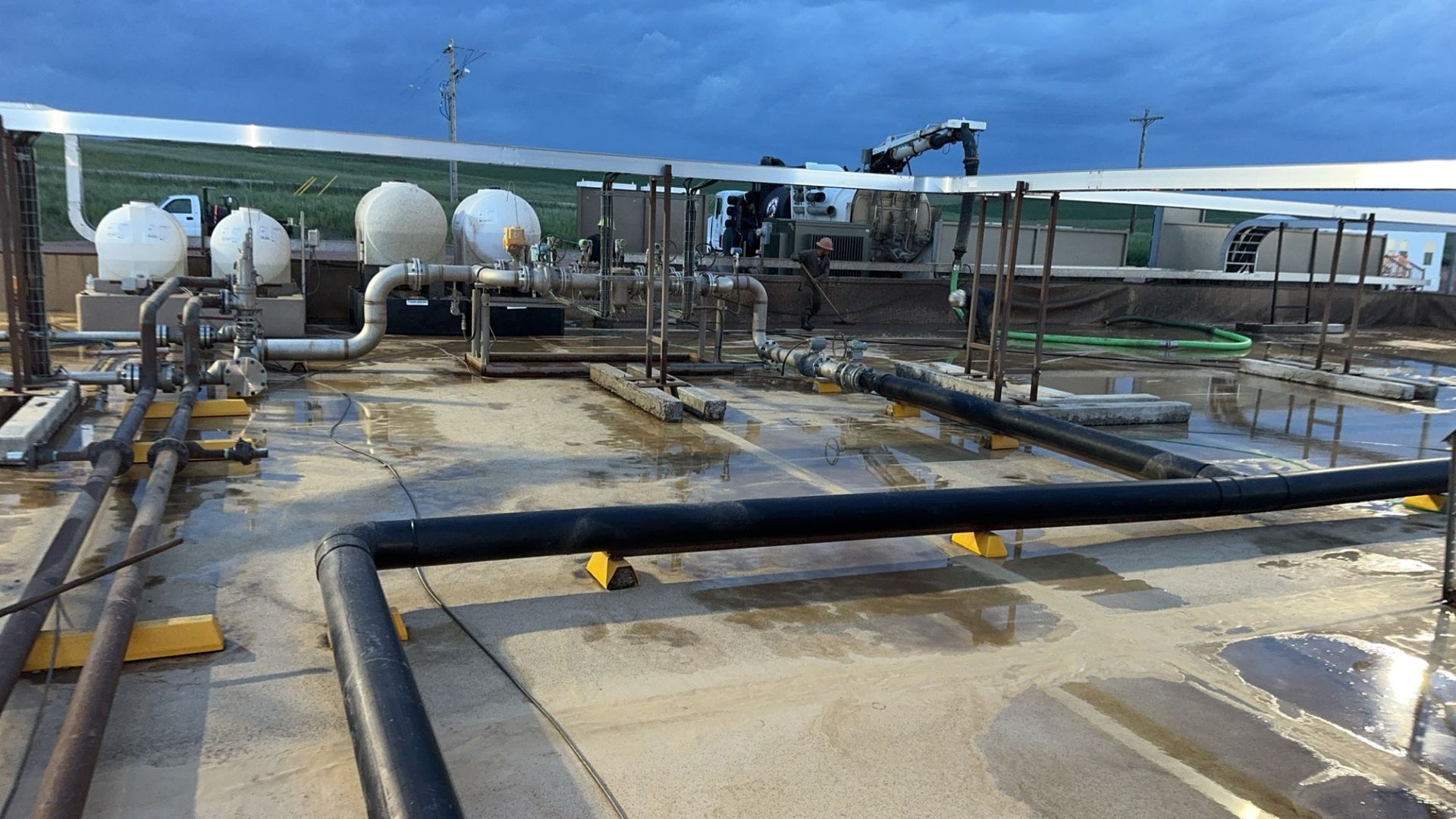 Industrial plant with pipes, tanks, and equipment on a concrete platform under a blue sky