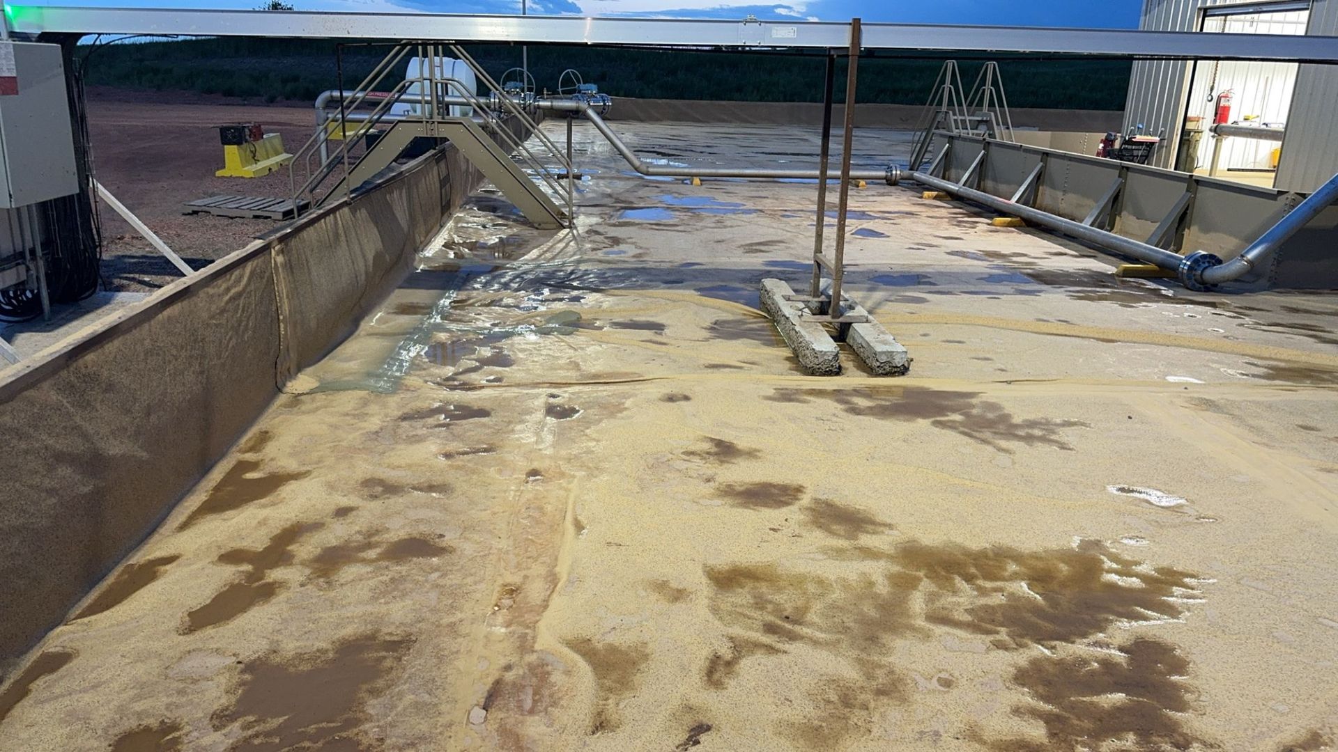 Damaged flooded rooftop with muddy water, debris, and a bent metal railing