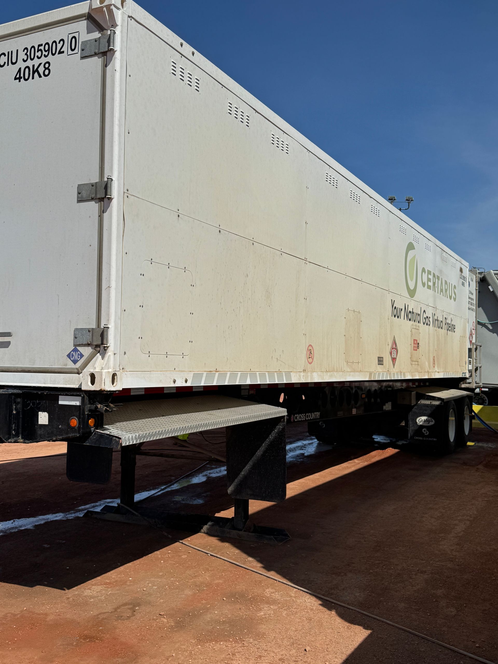 White cargo trailer parked on a wet lot under a blue sky