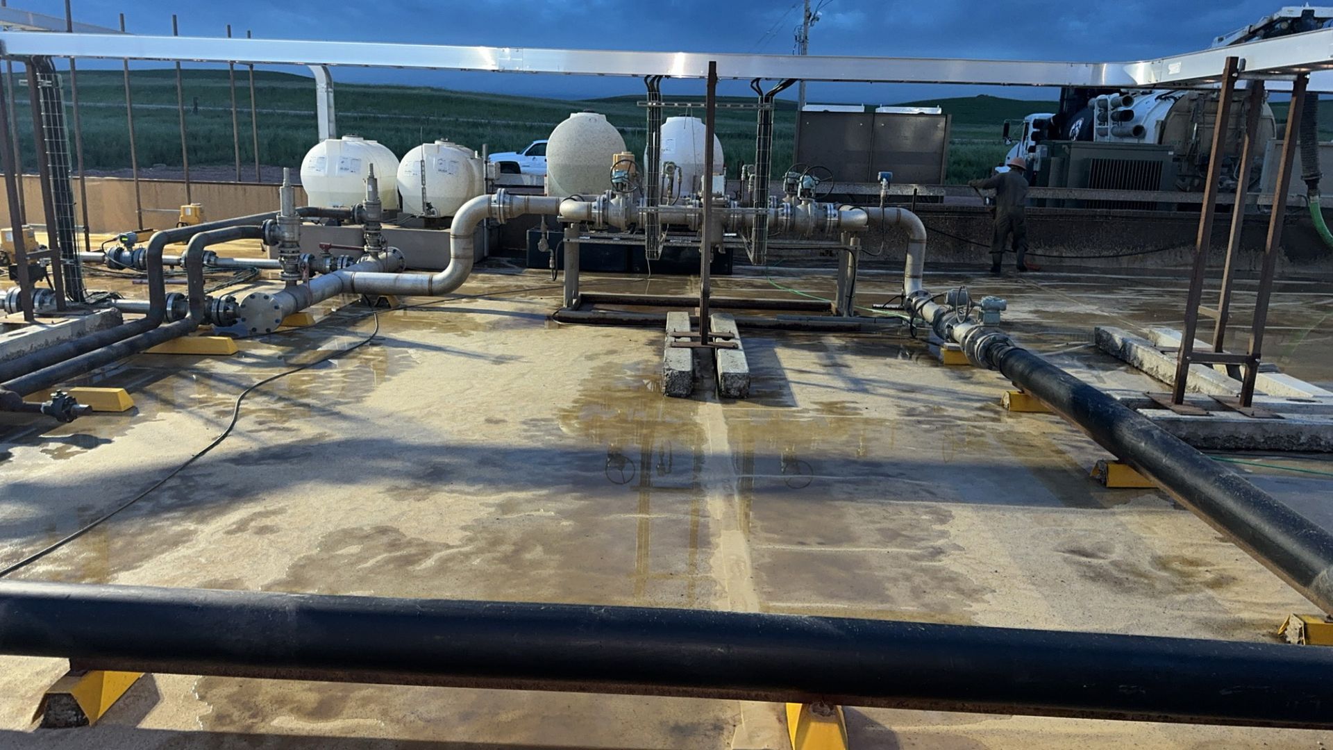 Industrial rooftop with large pipes, white tanks, and metal equipment under a clear blue sky