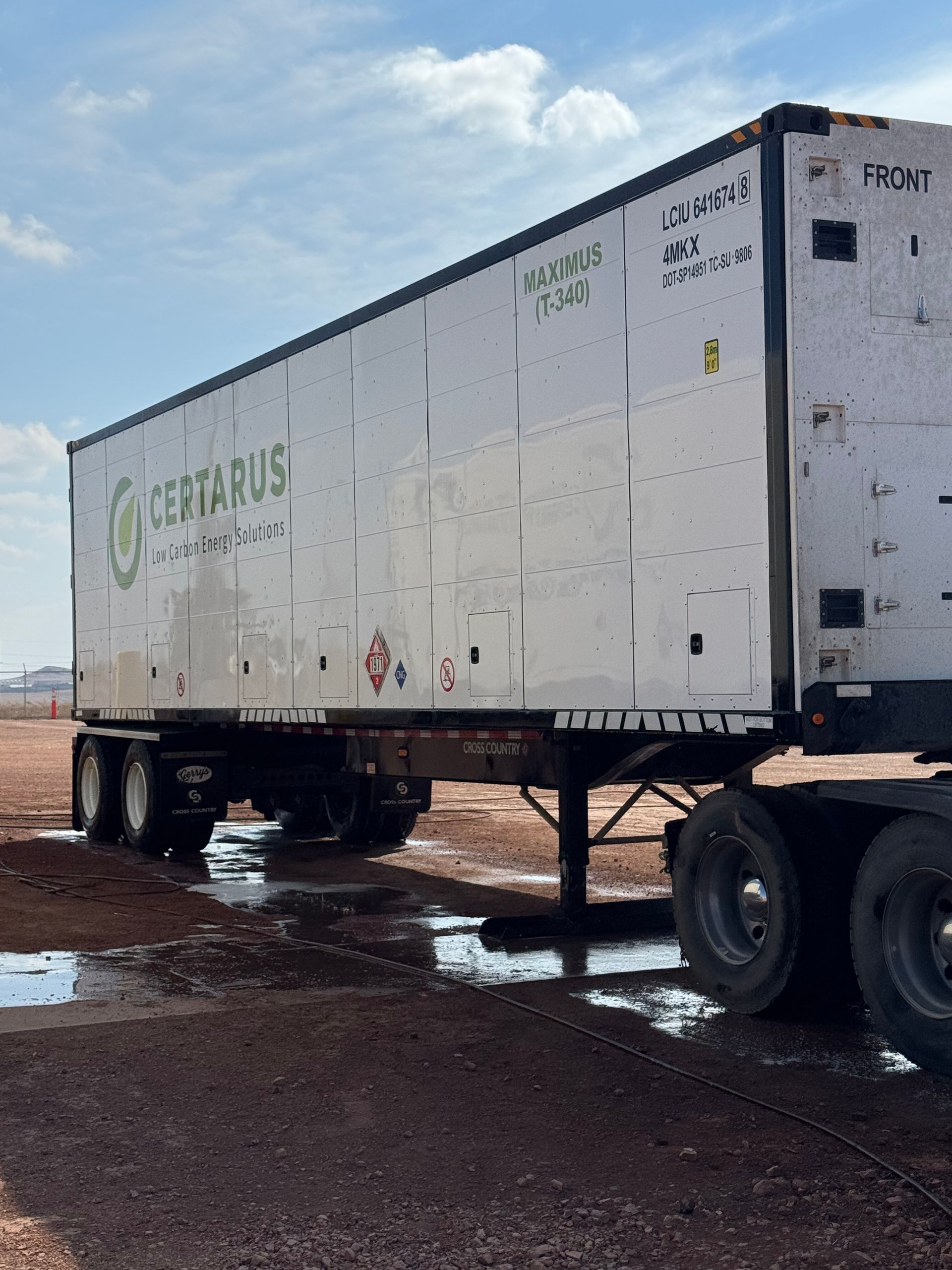 White semitrailer truck on a muddy lot with puddles under a cloudy sky
