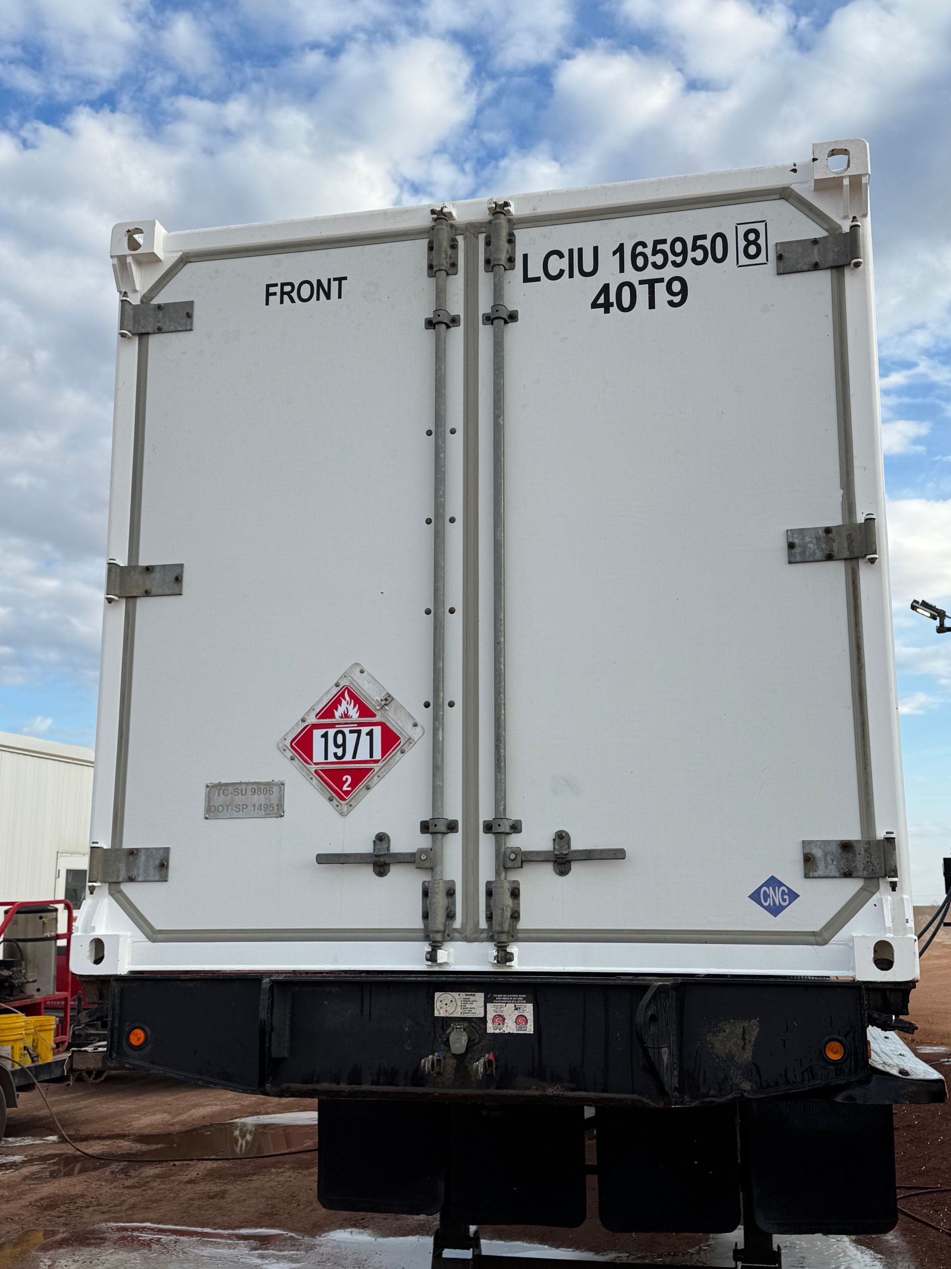 Rear view of a white refrigerated shipping container on a truck under a cloudy sky