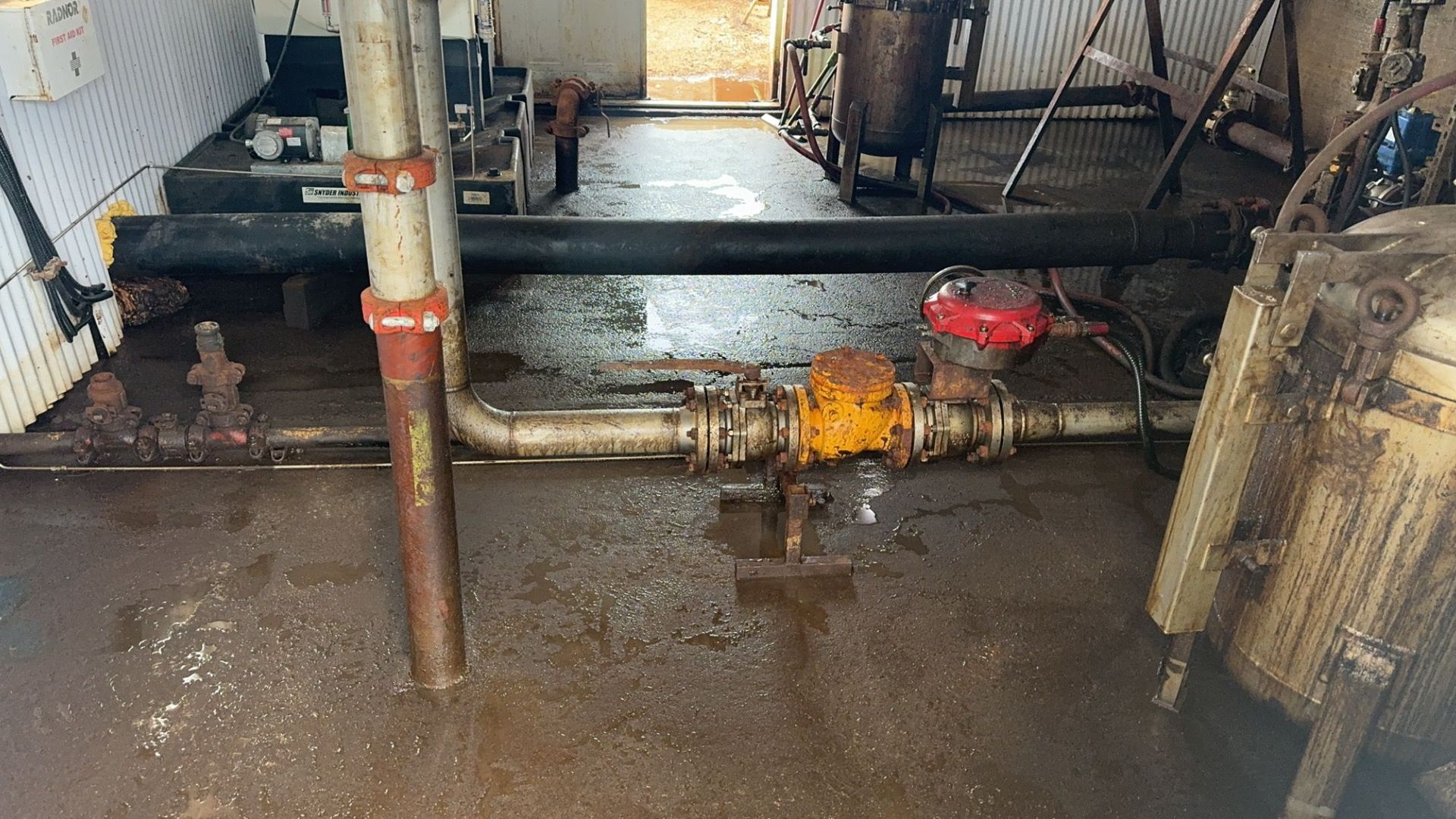 Flooded industrial basement with pipes and standing water on the floor