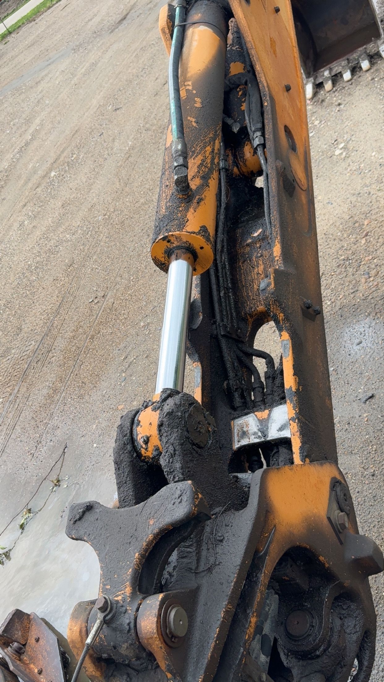 Close-up of an orange and black excavator arm with a hydraulic cylinder and bucket hinge.