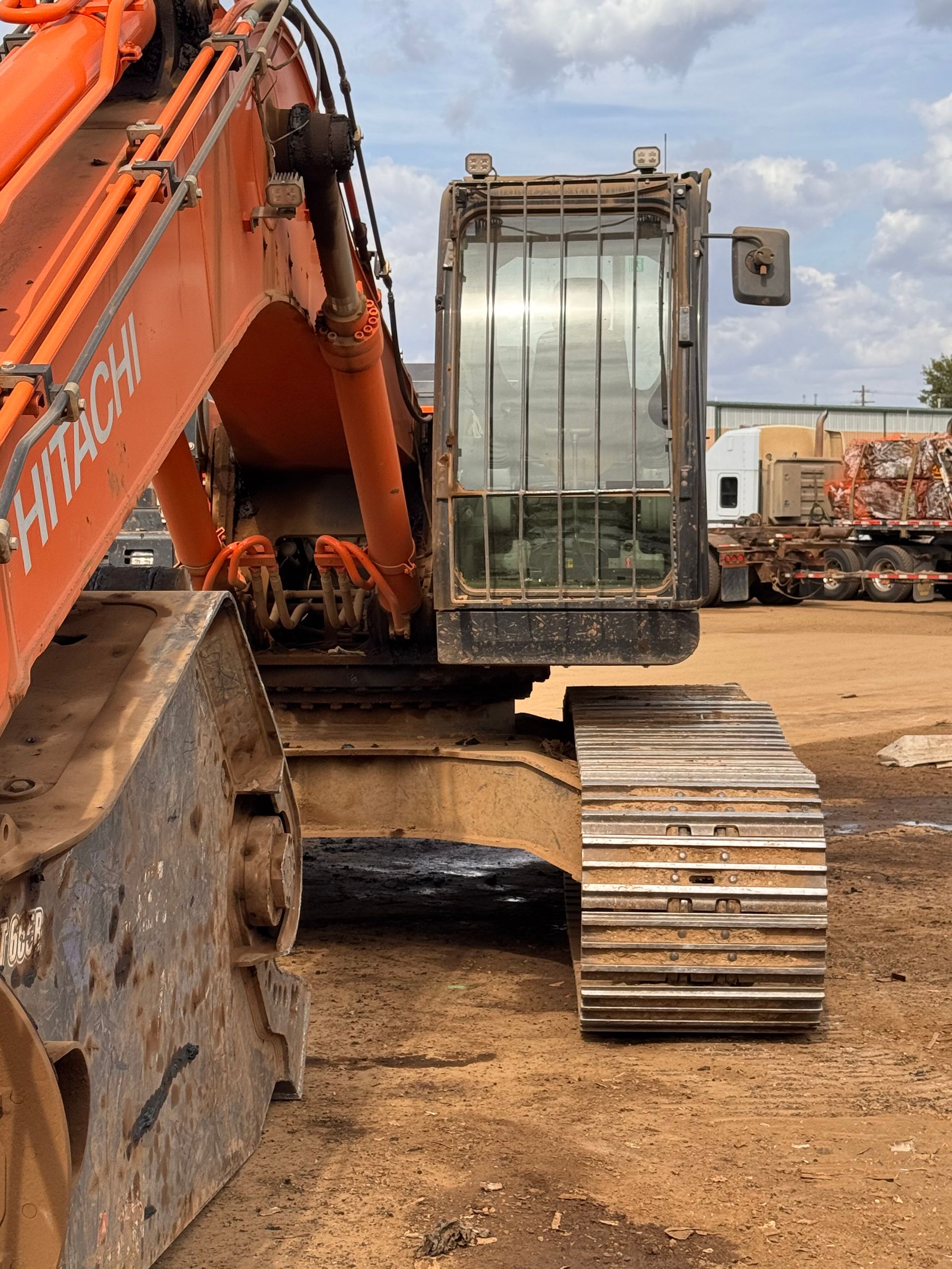 Orange excavator with a muddy cab and metal tracks at a construction site