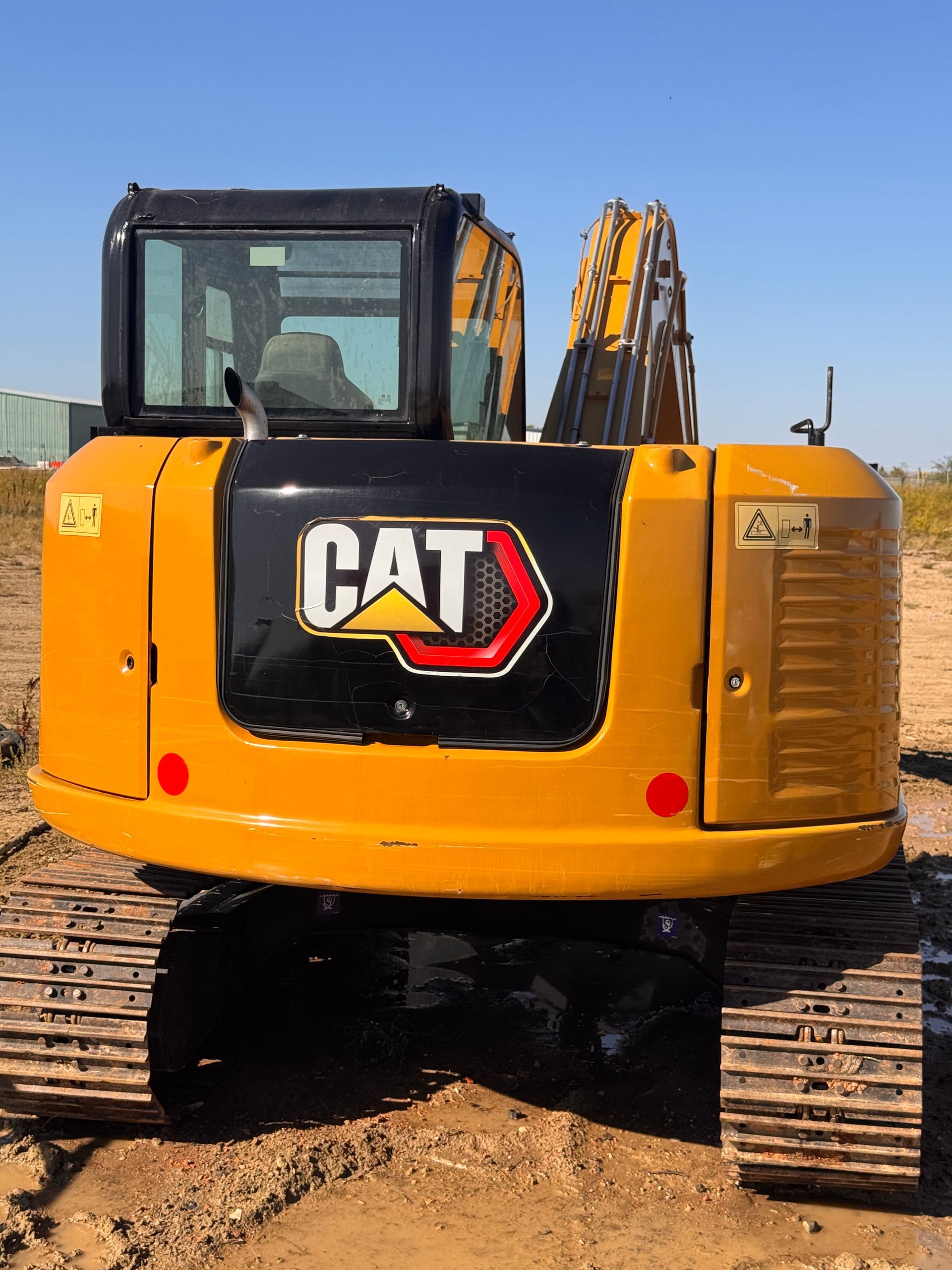 Rear view of a yellow CAT excavator on a dirt construction site