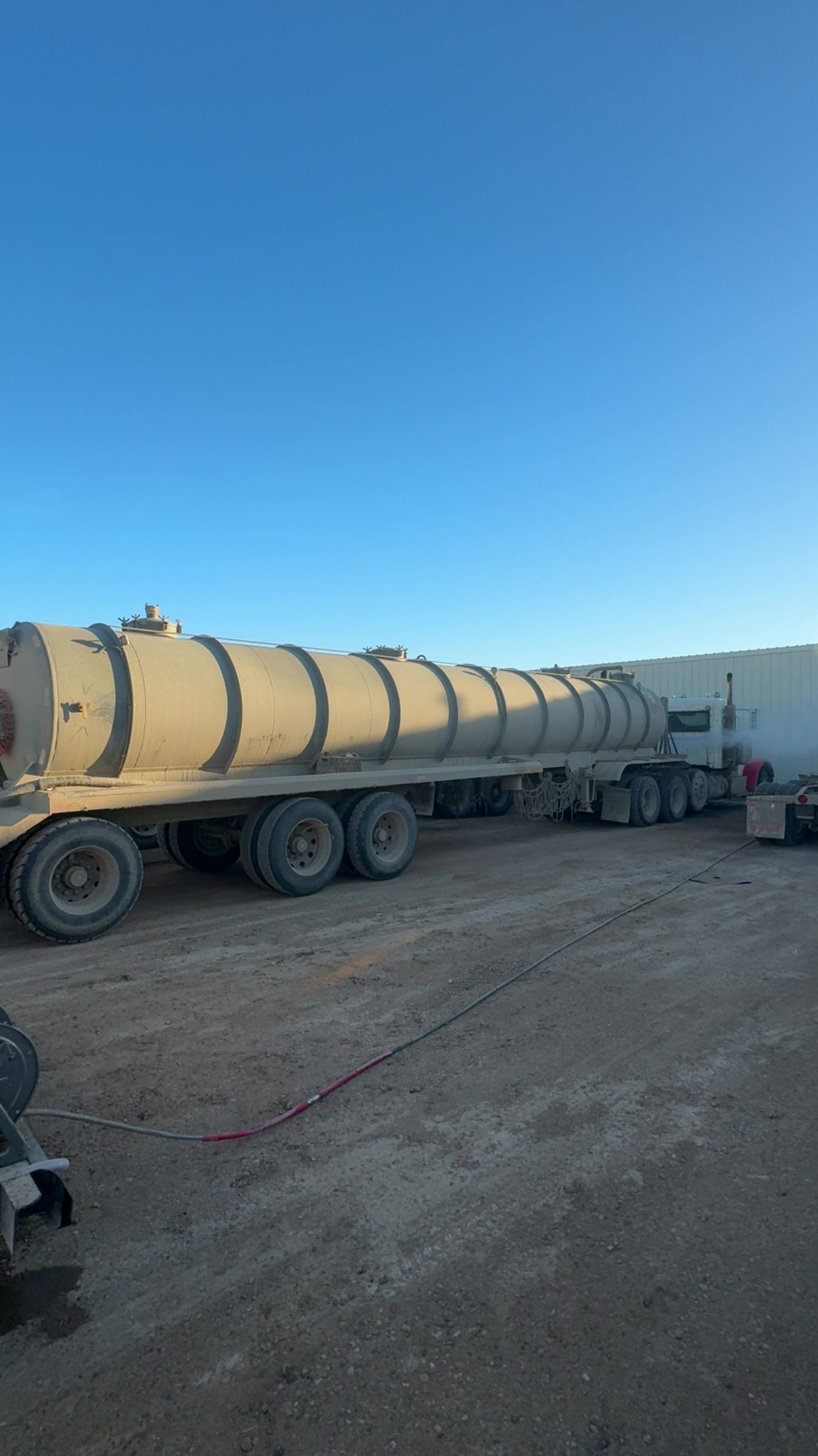 Yellow tanker trailer parked on a dirt lot under a clear blue sky