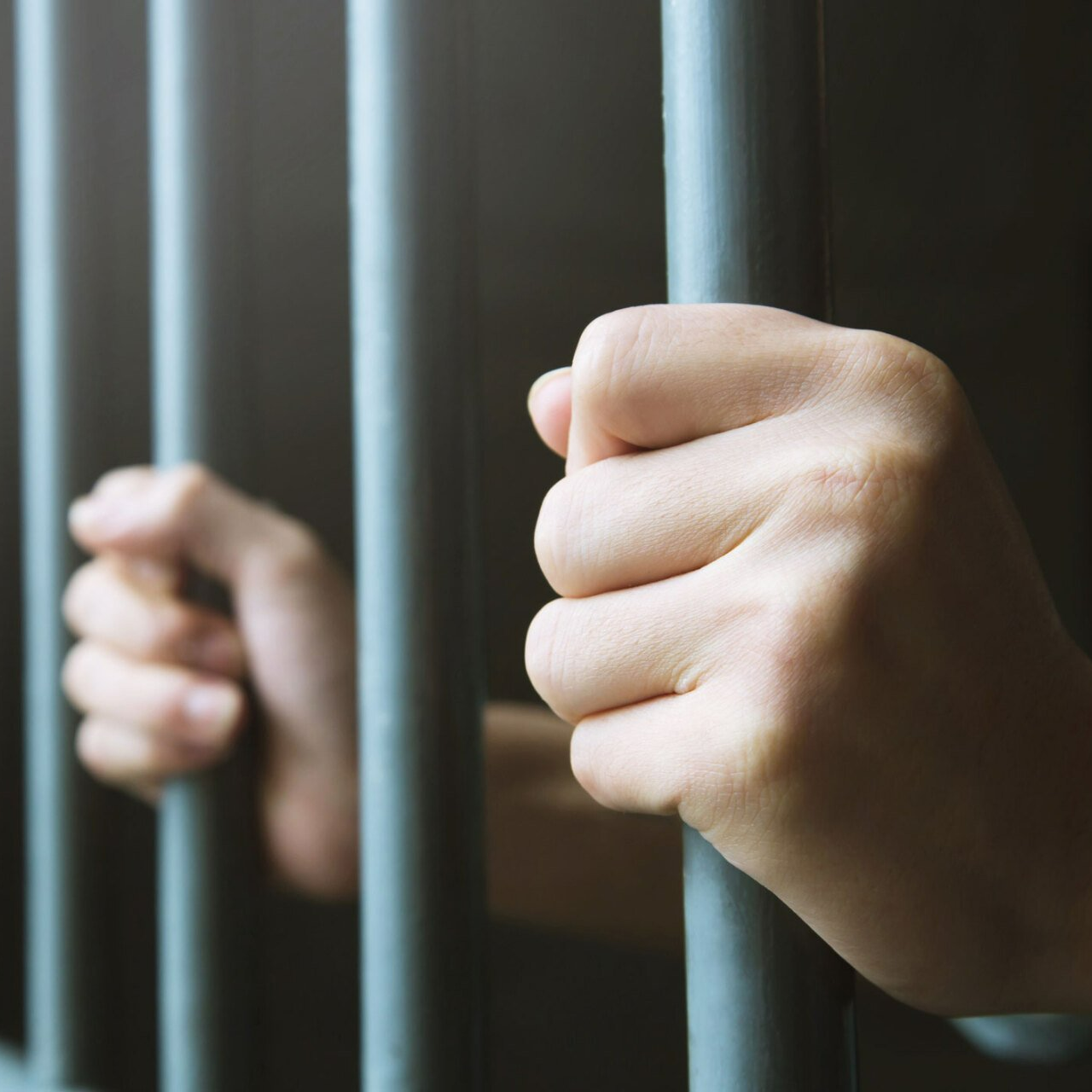 Hands holding prison bars — Live Oak, FL — Chauncey Bail Bond Inc Hands holding prison bars — Live Oak, FL — Chauncey Bail Bond Inc