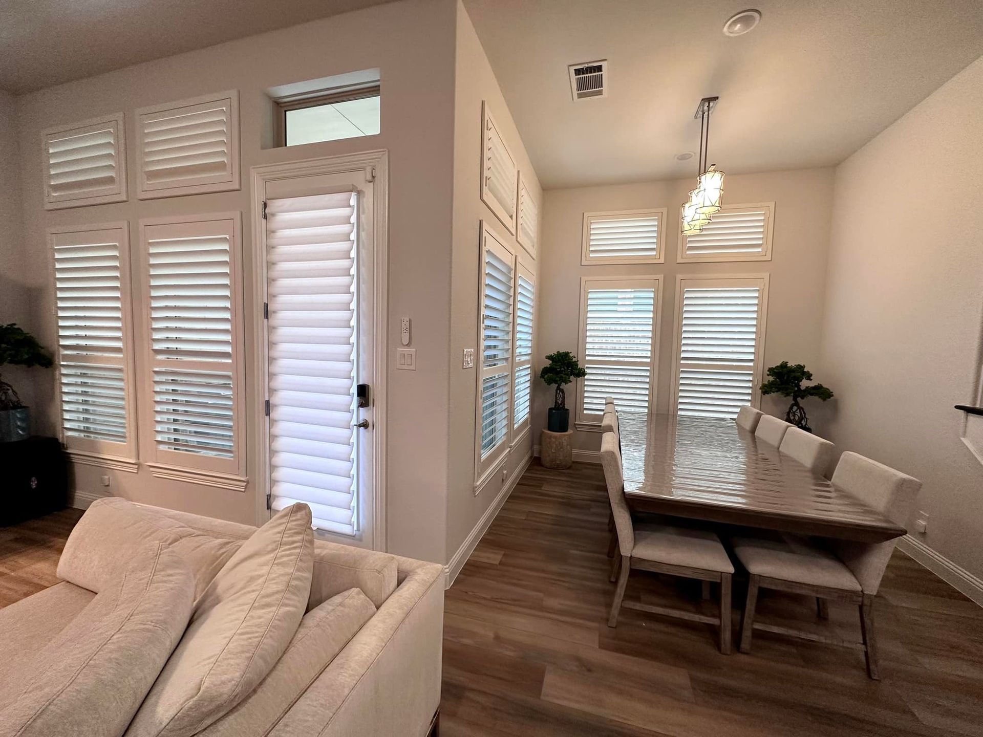 Bright interior with dining table, shutters, and beige sectional sofa.