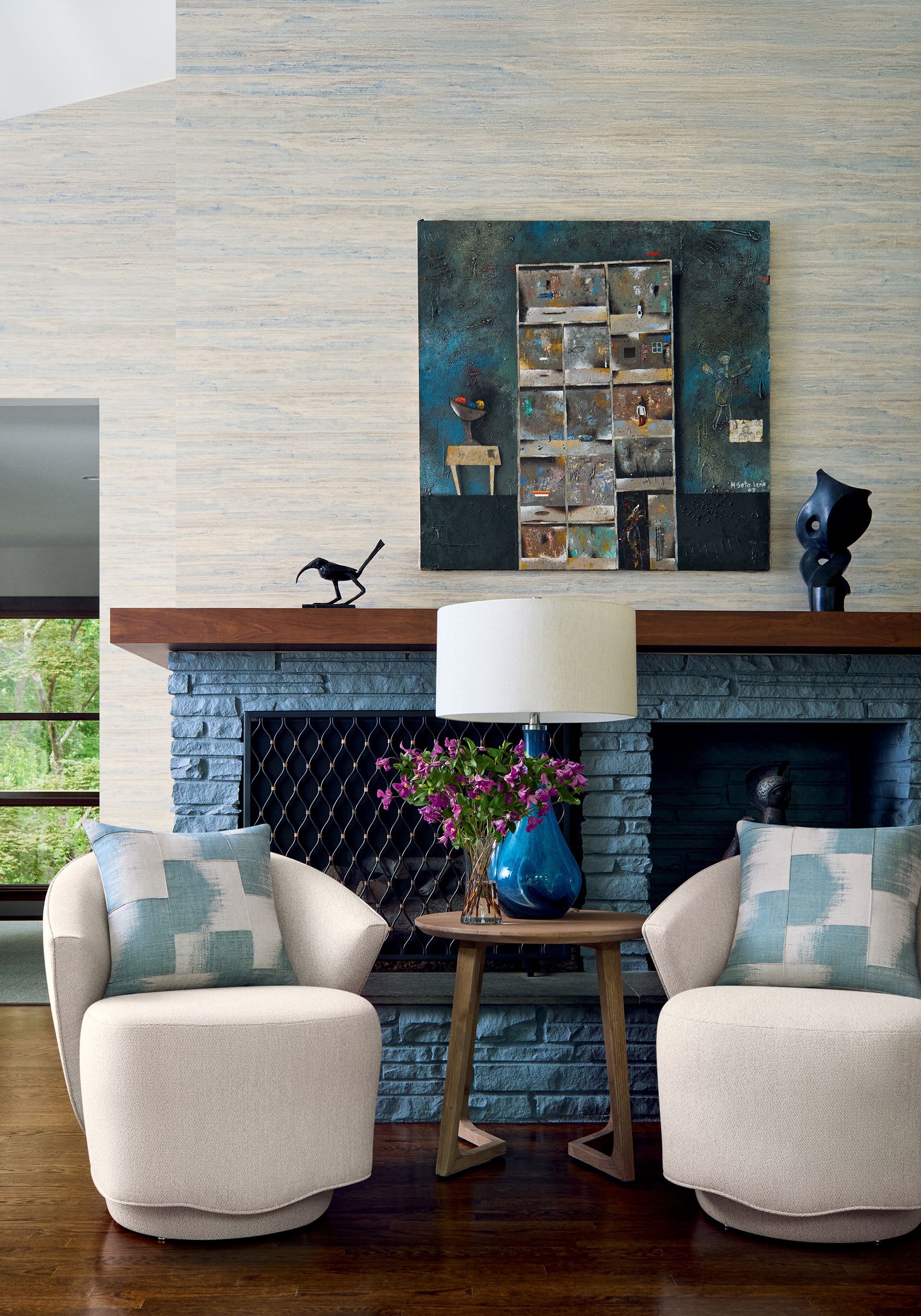 Living room with white chairs, fireplace, artwork, and a small table.