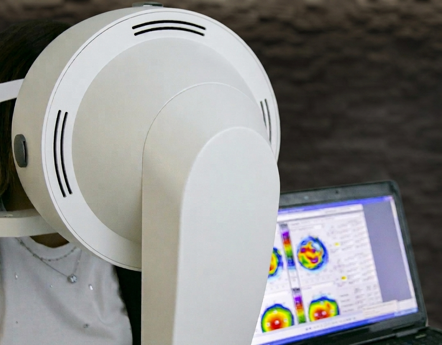 Uno scanner per immagini mediche accanto a un computer portatile che mostra mappe di calore colorate della scansione cerebrale.