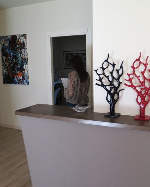 Bancone interno con sculture decorative a forma di rami neri e rossi; una persona è in piedi sulla soglia di una porta alle sue spalle.