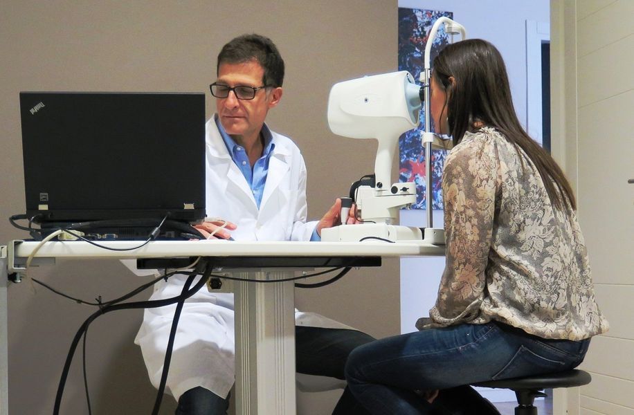 Un medico visita un paziente accanto a un apparecchio per esami oculistici in una clinica.