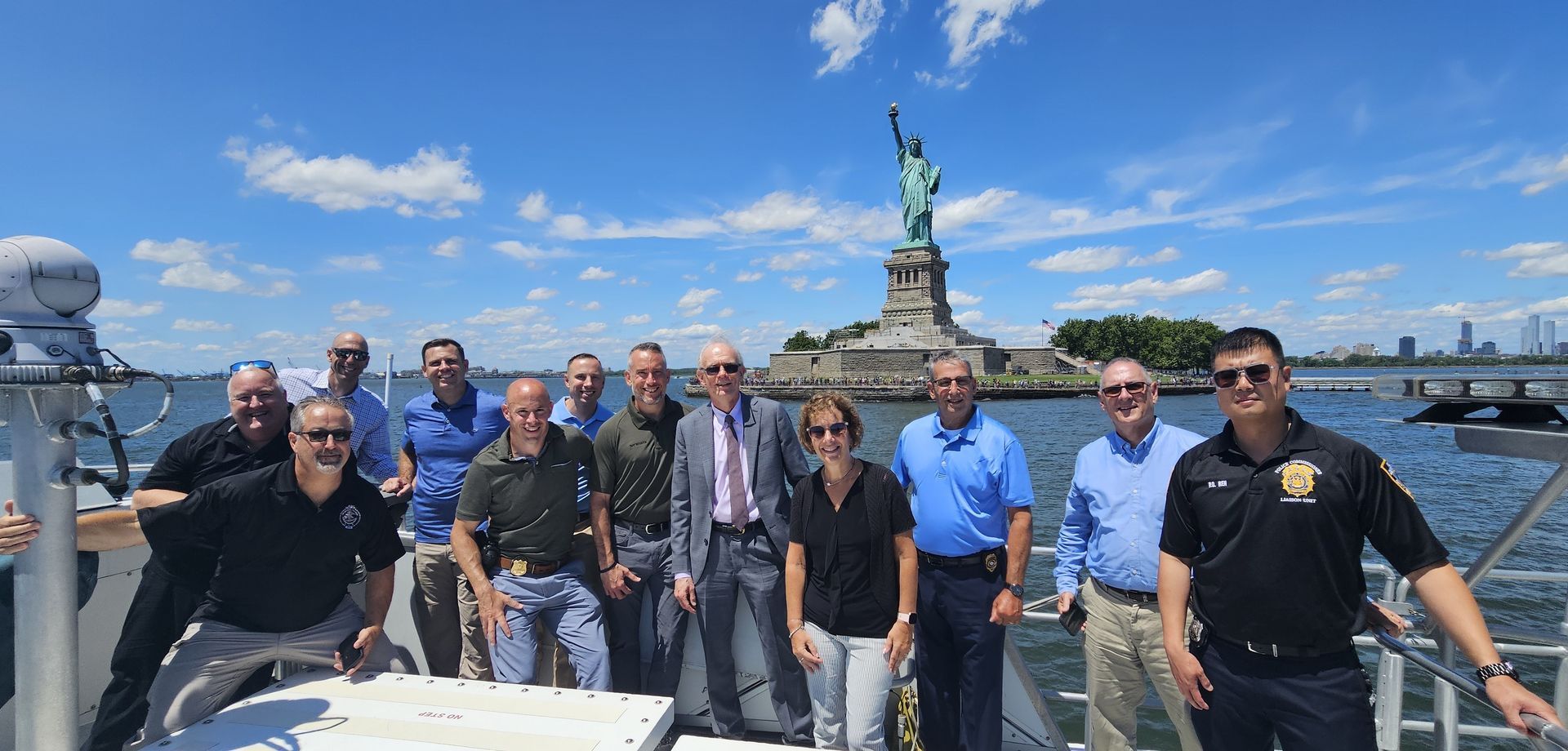 A group of people are posing for a picture in front of the statue of liberty.