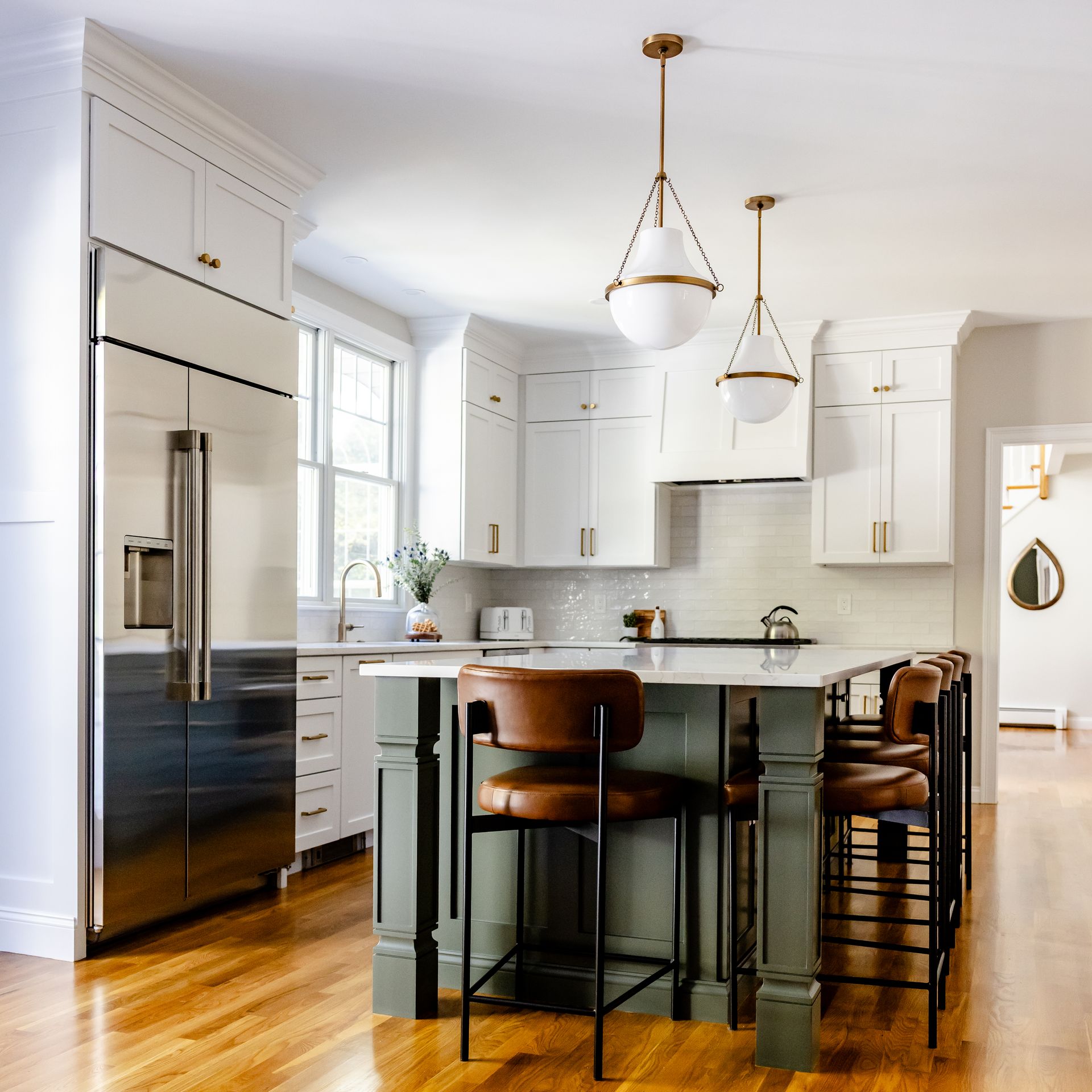 White Shaker cabinets, green island and brass pendants