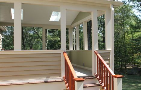Porch with white columns and beige siding, reached by wooden steps with red railings.