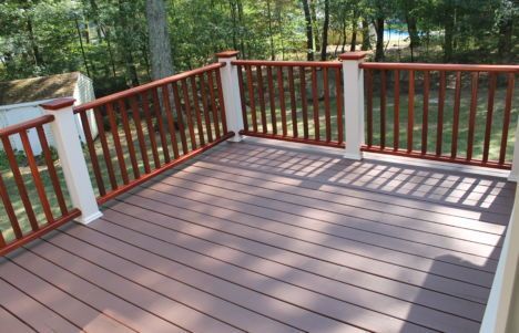 Wooden deck with red railing overlooking a wooded yard