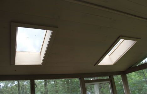 Ceiling with two skylights above windows in a room with trees outside