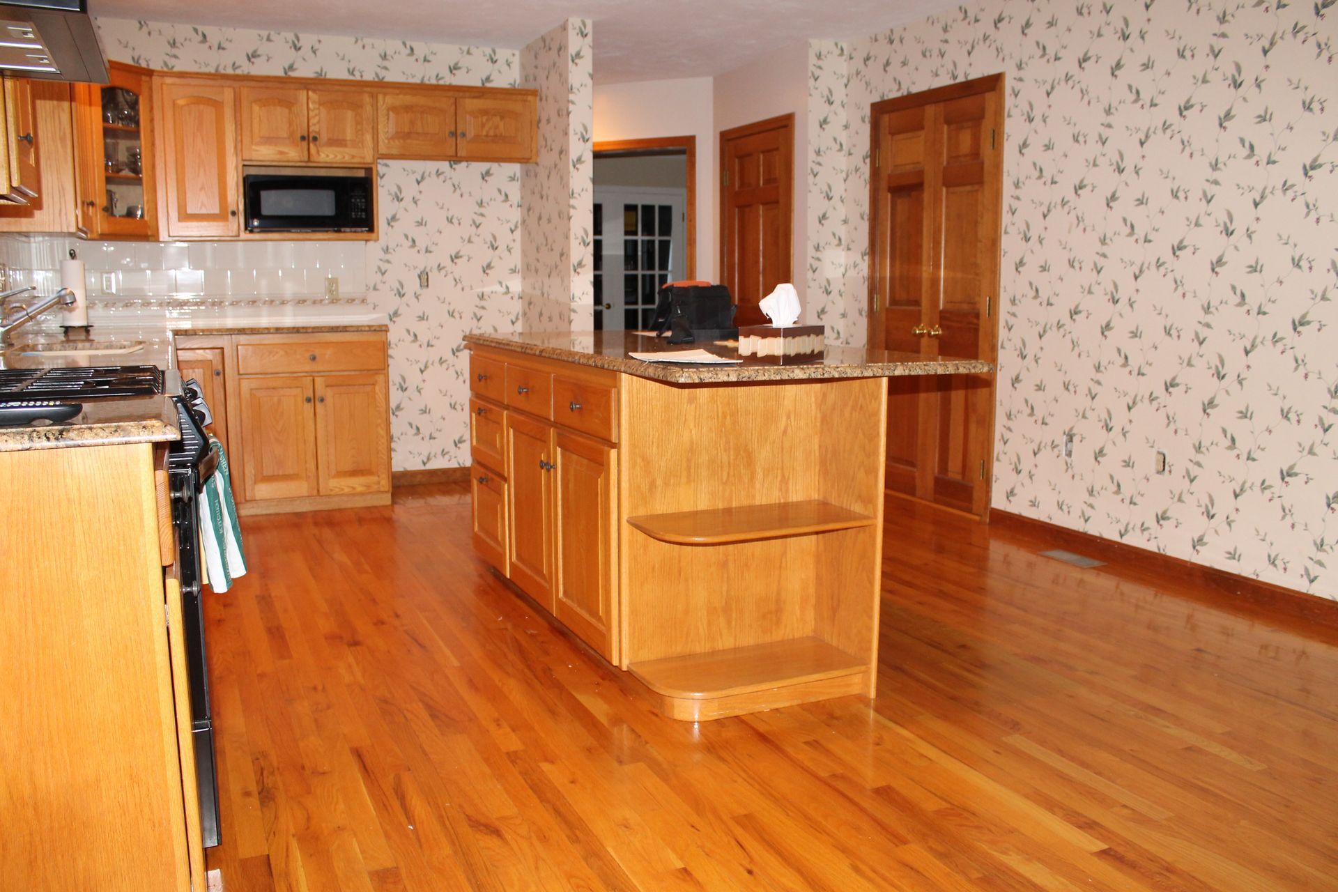 Spacious kitchen with wooden cabinets, central island, and hardwood floors.