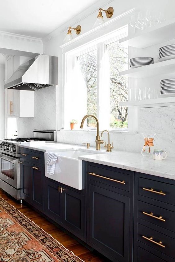 Bright modern kitchen with dark cabinets, white countertops, farmhouse sink, and brass fixtures