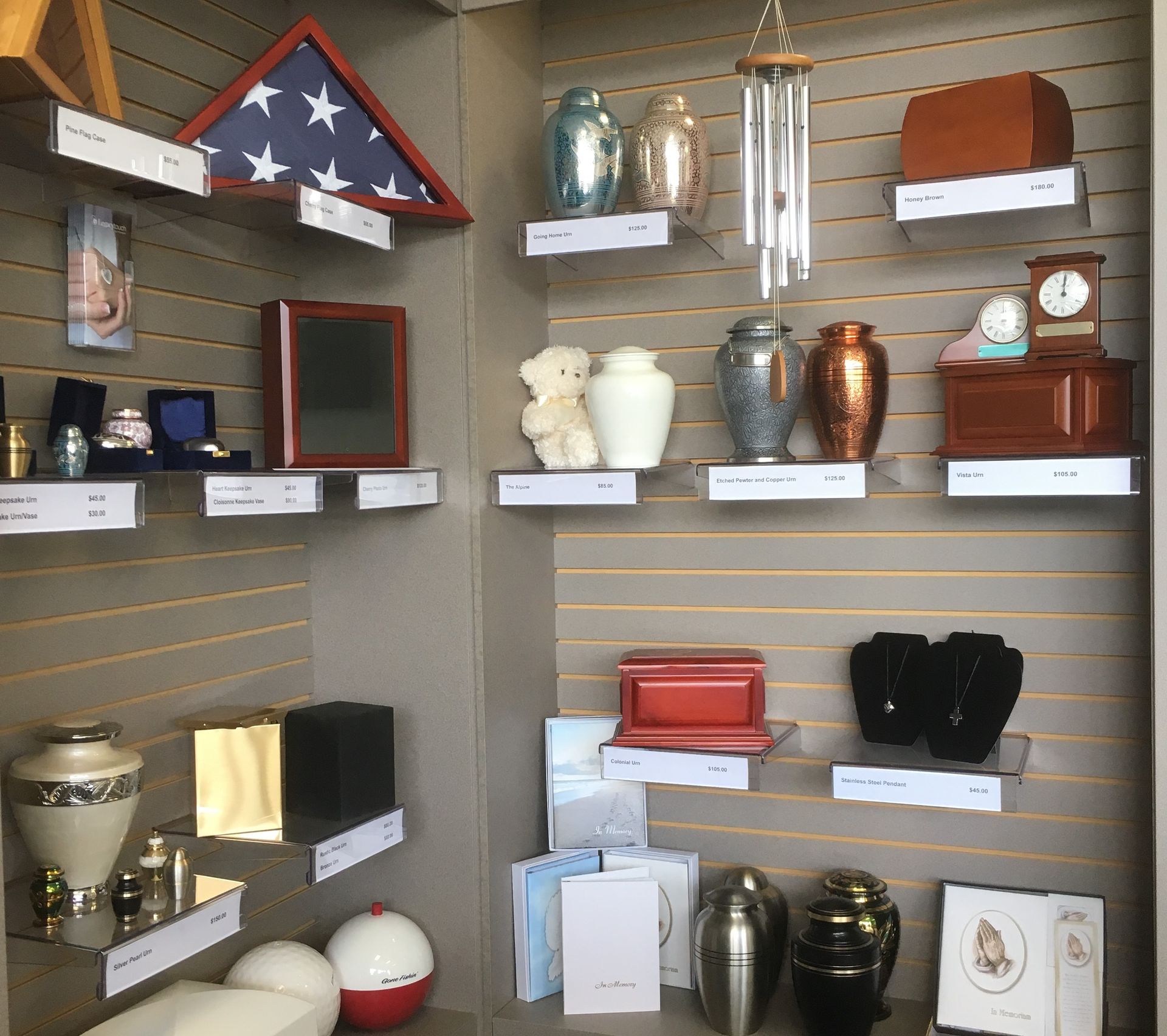 Display of assorted memorial urns and keepsakes on wall shelves in a shop