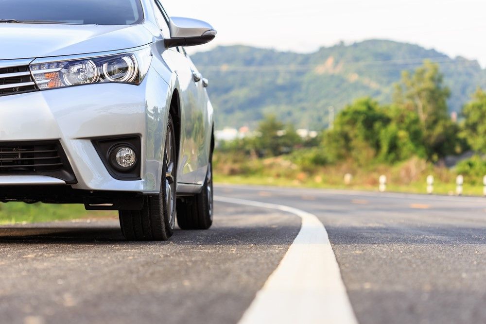 A Silver Car Is Driving Down a Curvy Road — Greenaway's Taxi in Harrington, NSW
