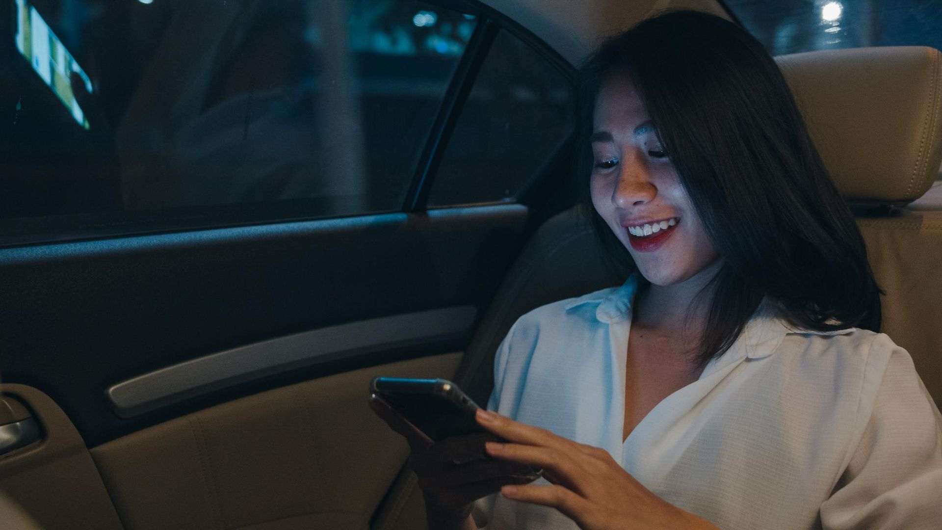 A Woman Is Sitting in The Back Seat of A Car Using a Cell Phone — Greenaway's Taxi in Comboyne, NSW