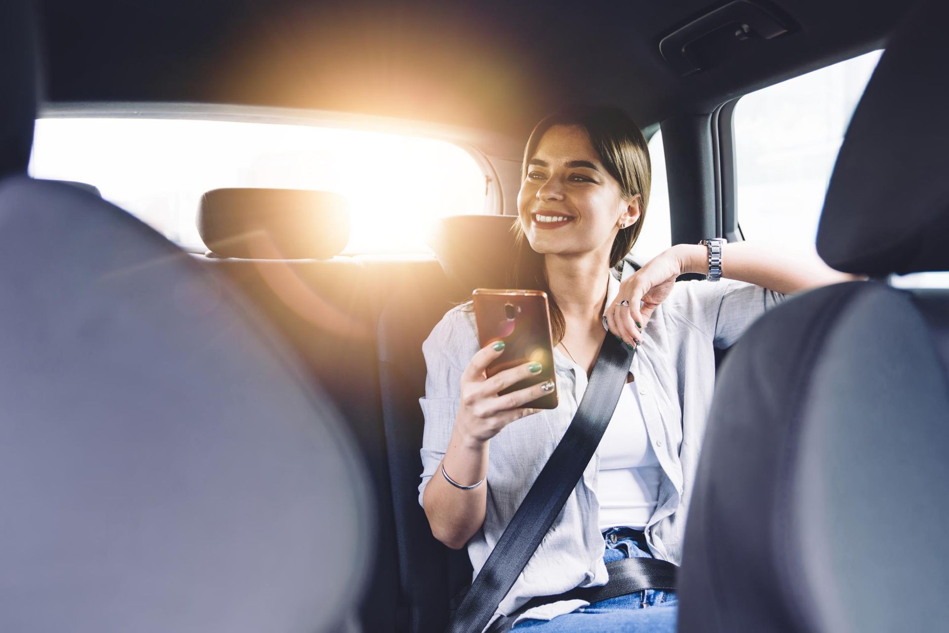 A Woman Is Sitting in The Back Seat of A Car Looking at Her Phone — Greenaway's Taxi in Forster, NSW